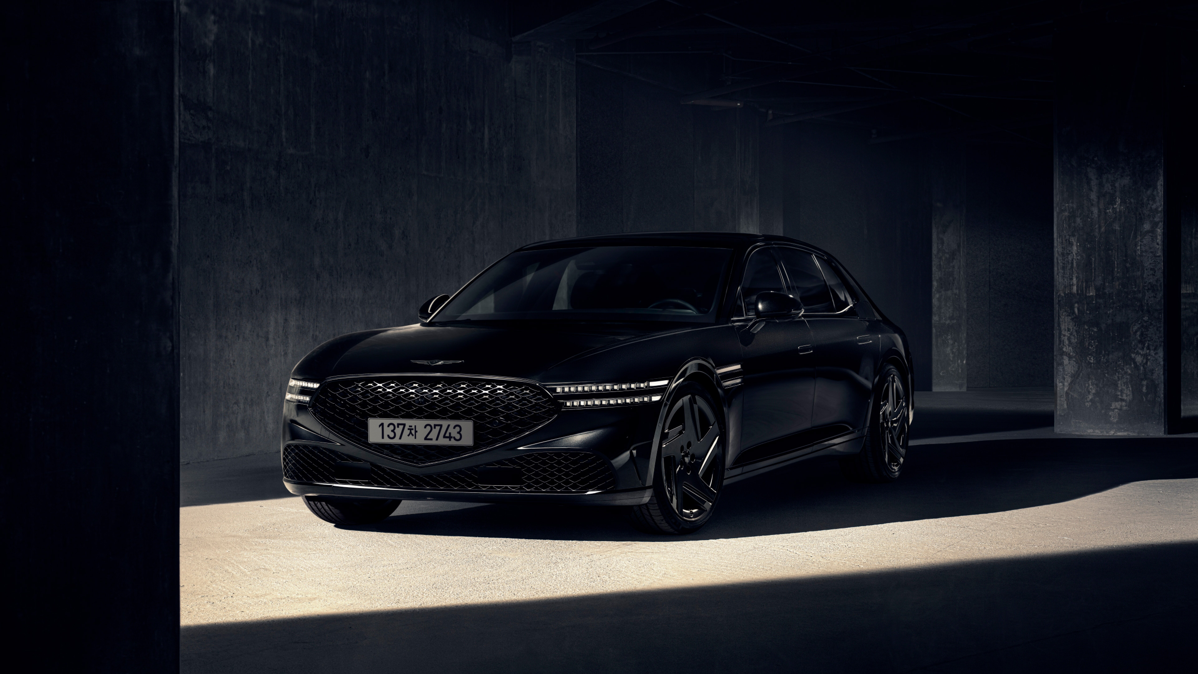 기둥 사이에 서 있는 제네시스 G90 블랙