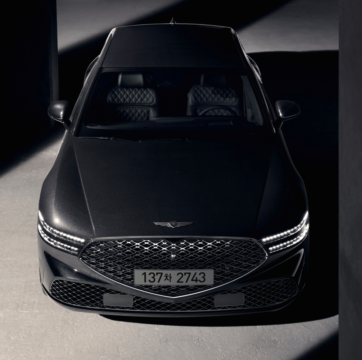 기둥 사이에 서 있는 G90 블랙의 앞모습