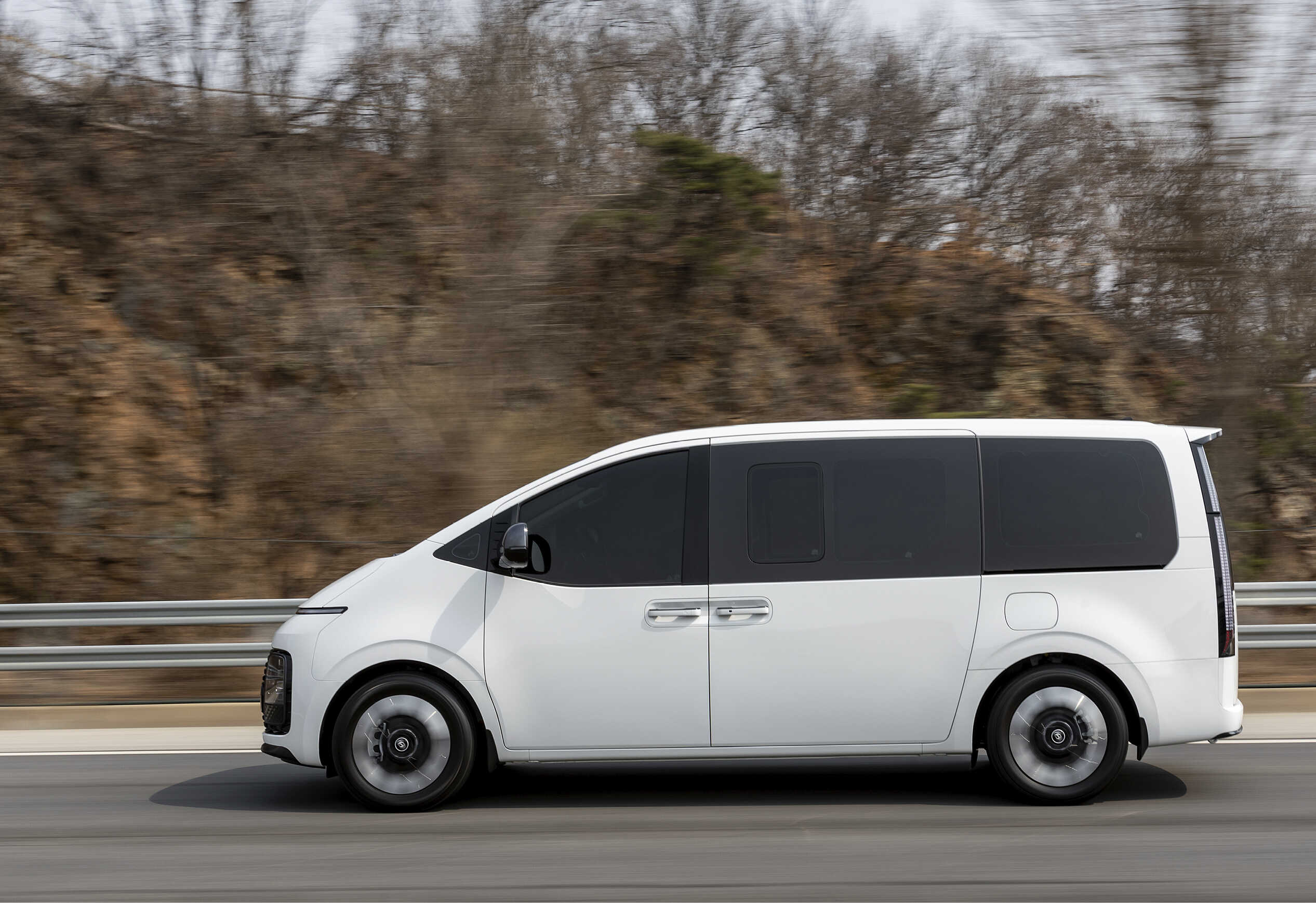 고속도로를 빠르게 주행하는 흰색 스타리아의 정측면 모습