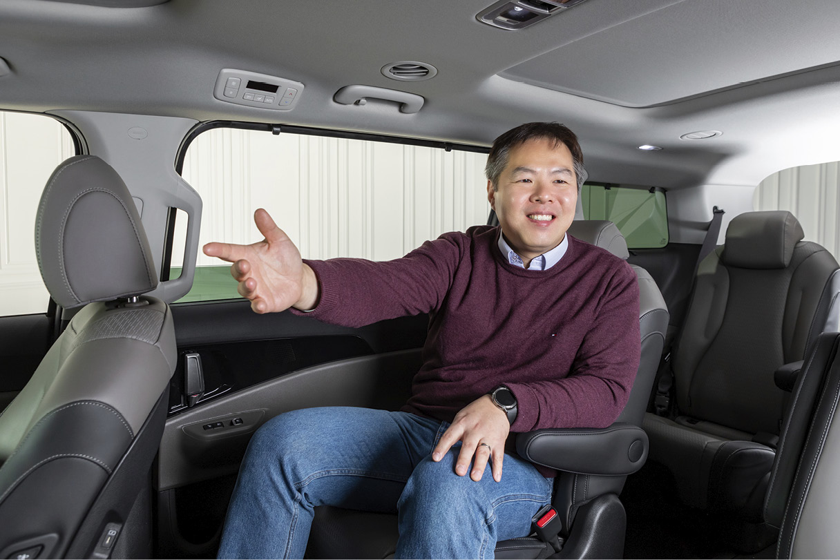 뒷좌석에 앉은 남성이 조수석을 향해 빨을 뻗고 웃는 모습