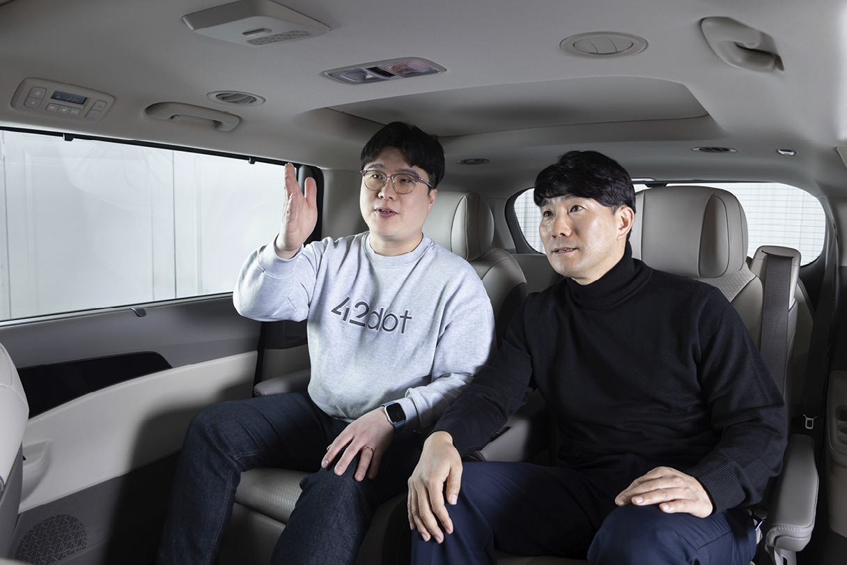 뒷좌석에 앉은 남성 두 명이 정면을 응시한 모습