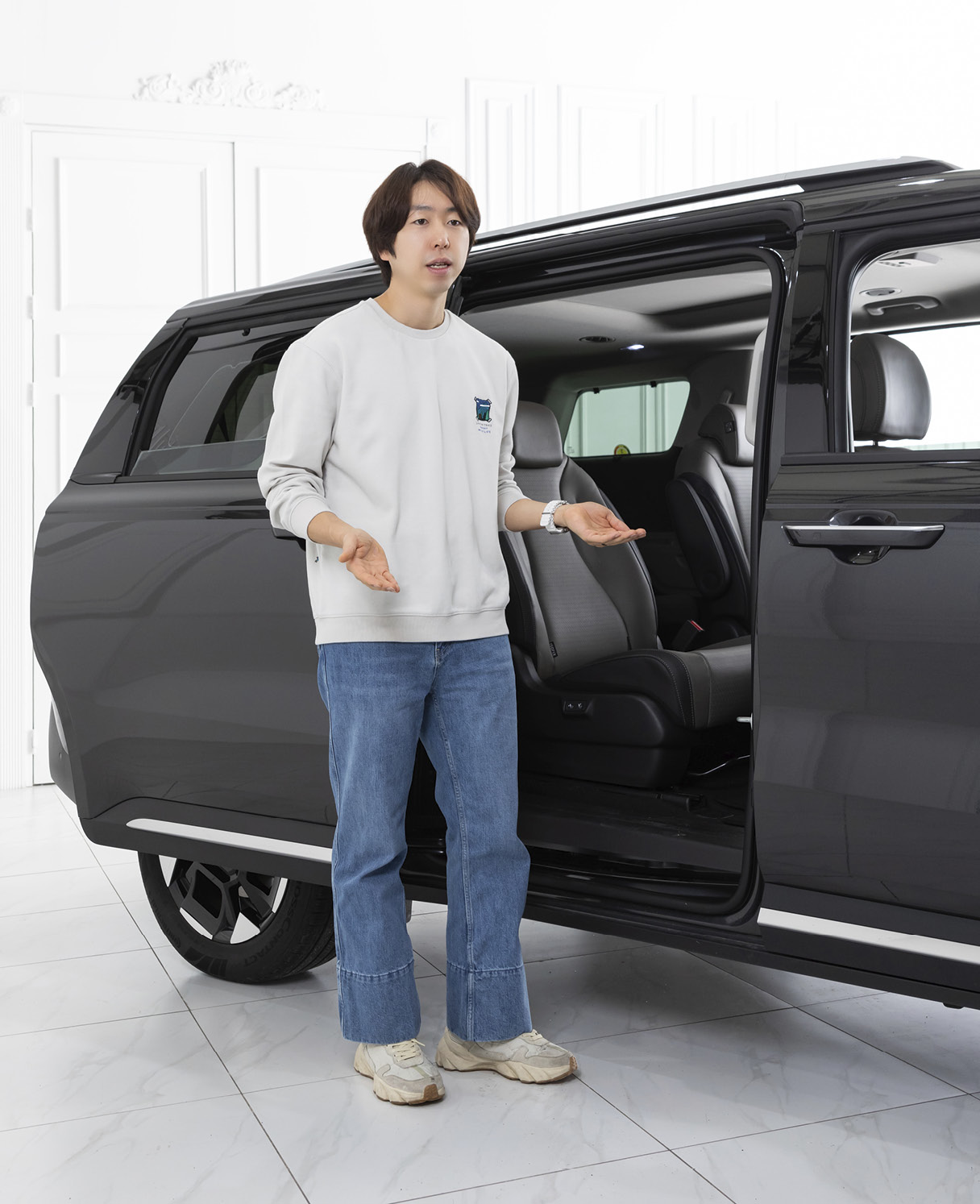 남성이 슬라이딩 도어가 열린 미니밴 옆에 서서 설명하는 모습