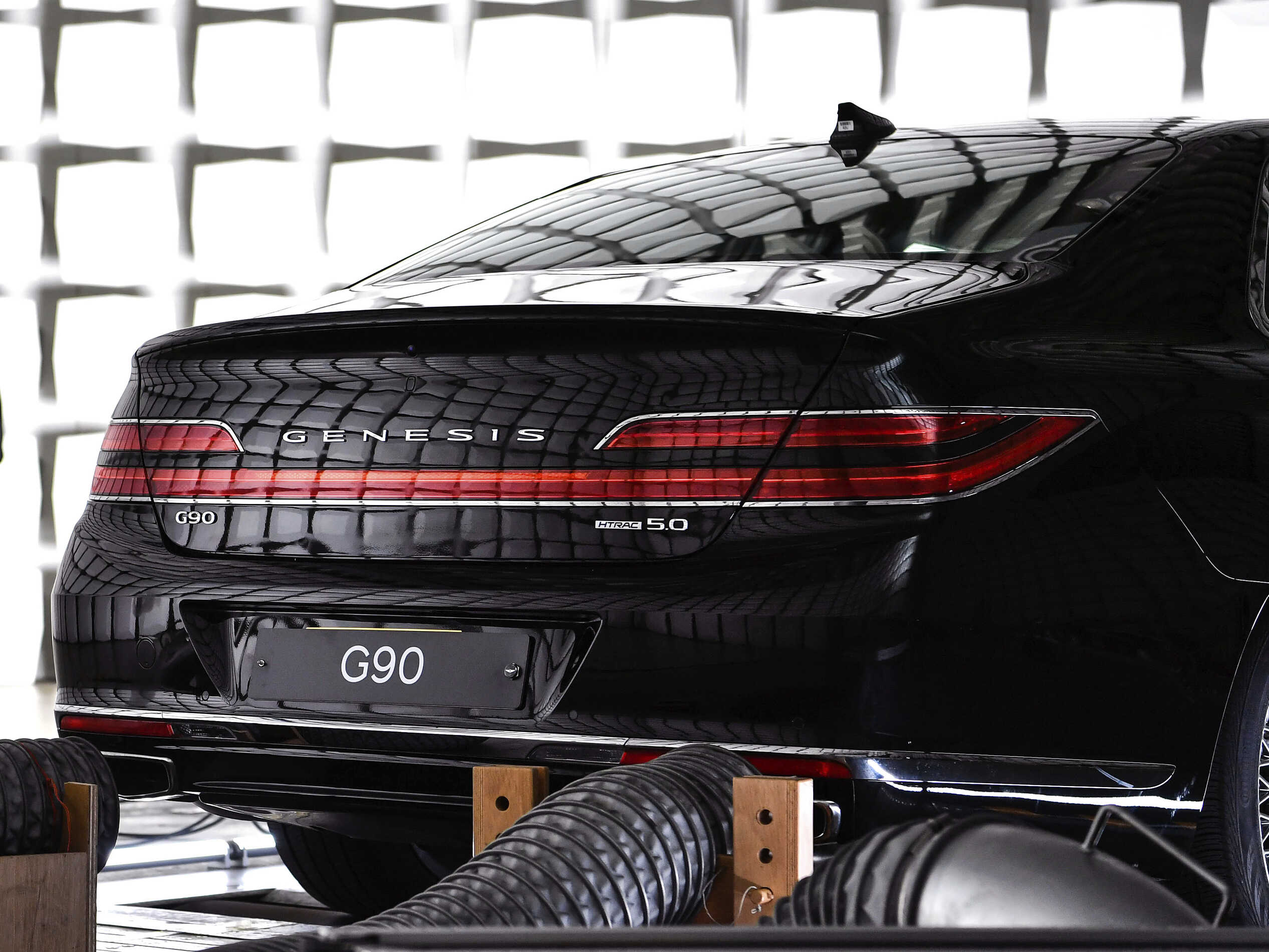 실험실 내부에 놓인 검정색 세단 머플러에 배기가스 흡입 장치가 연결된 모습