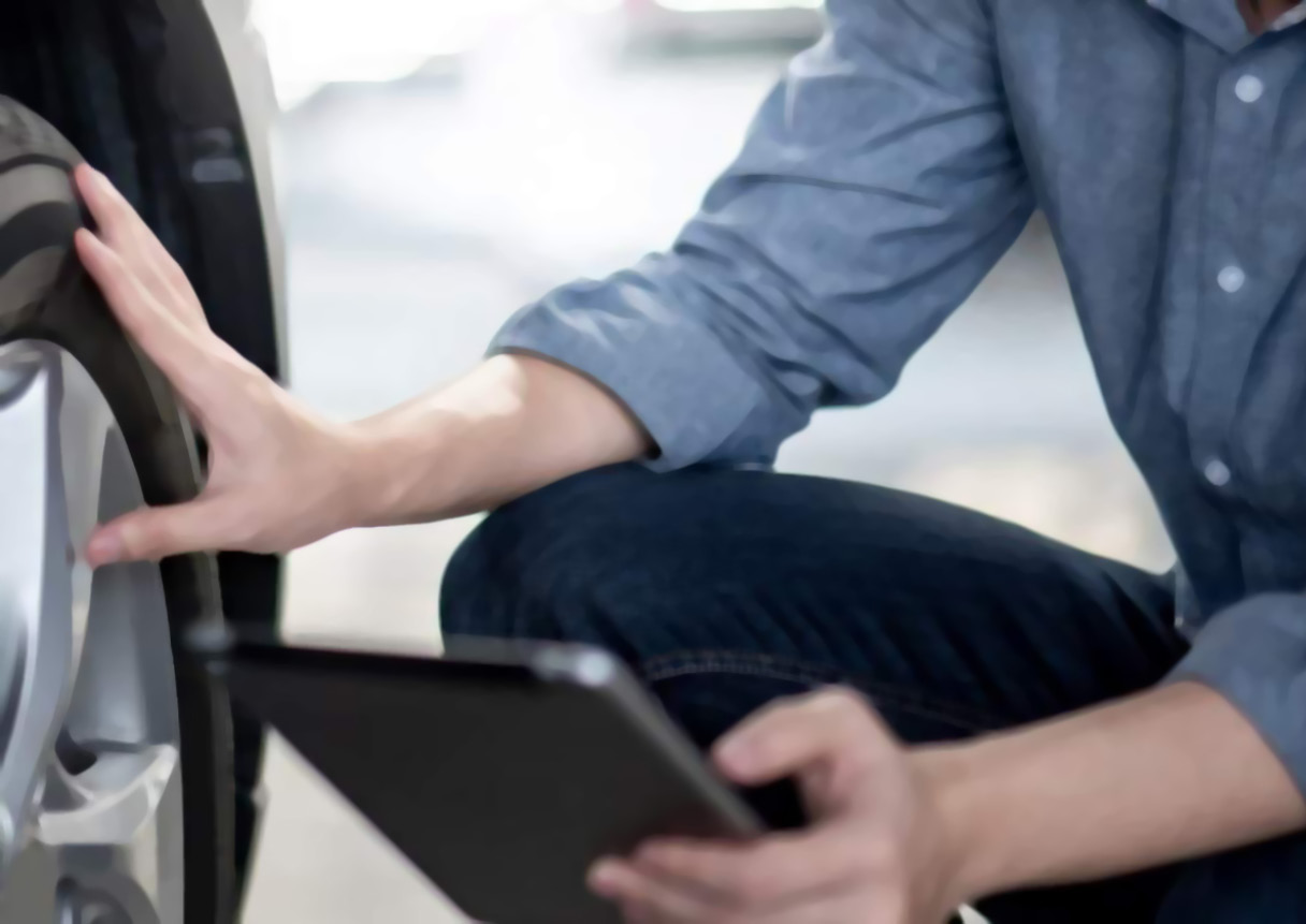 태블릿을 보며 타이어를 체크하고 있는 남자의 모습