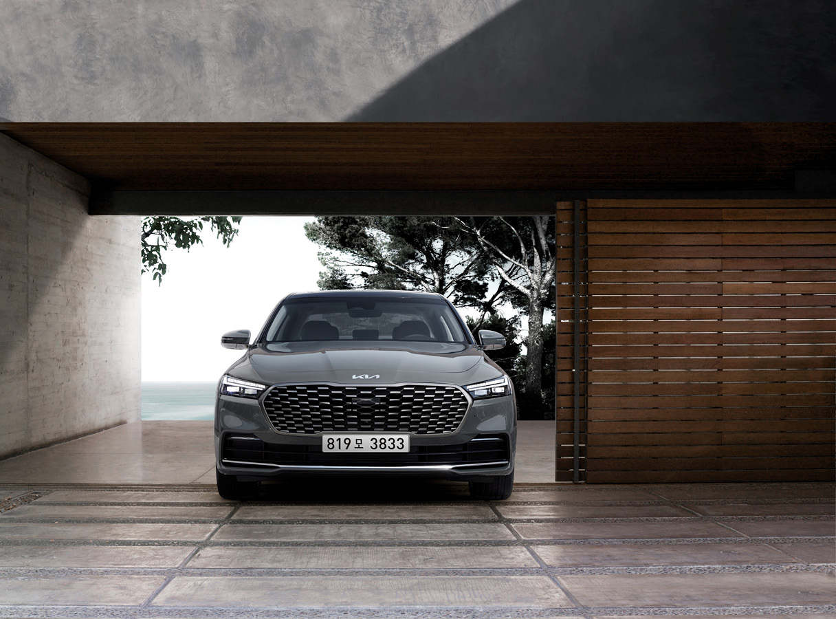 커다란 나무 문과 서있는 기아 K9의 전면