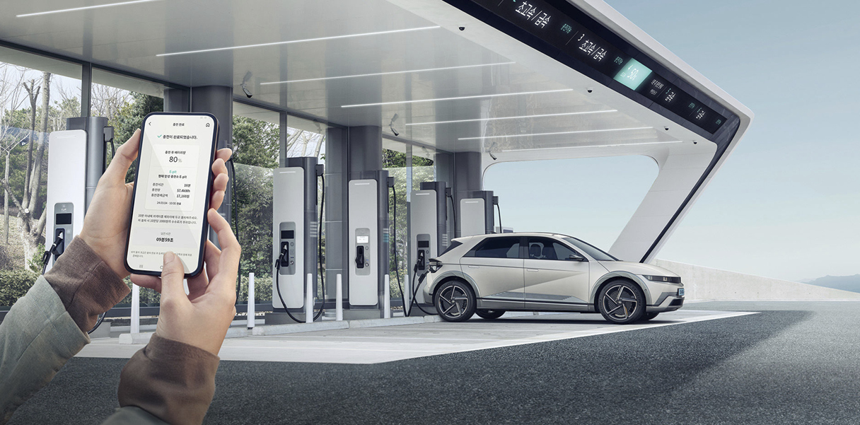 충전 중인 아이오닉 5의 전측면과 스마트폰을 쥐고 있는 손