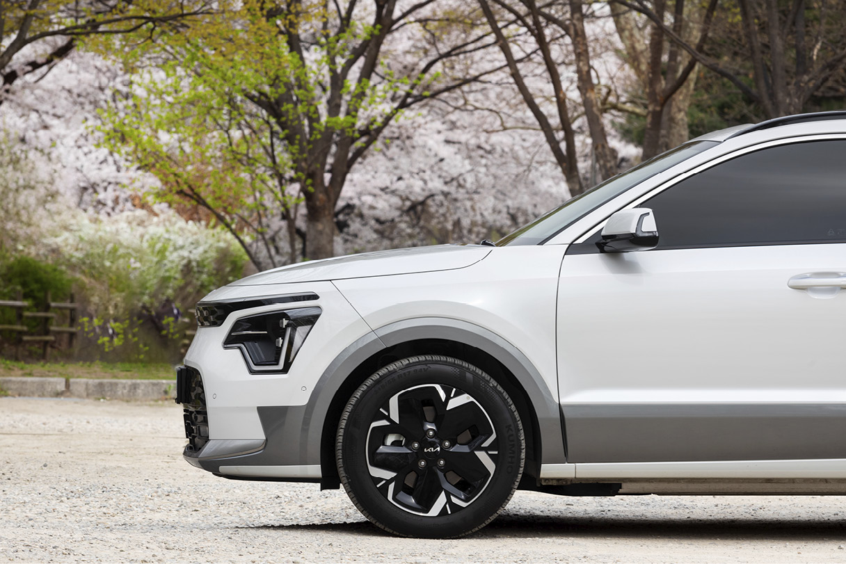 화사한 꽃들을 배경으로 서 있는 니로 EV의 측면