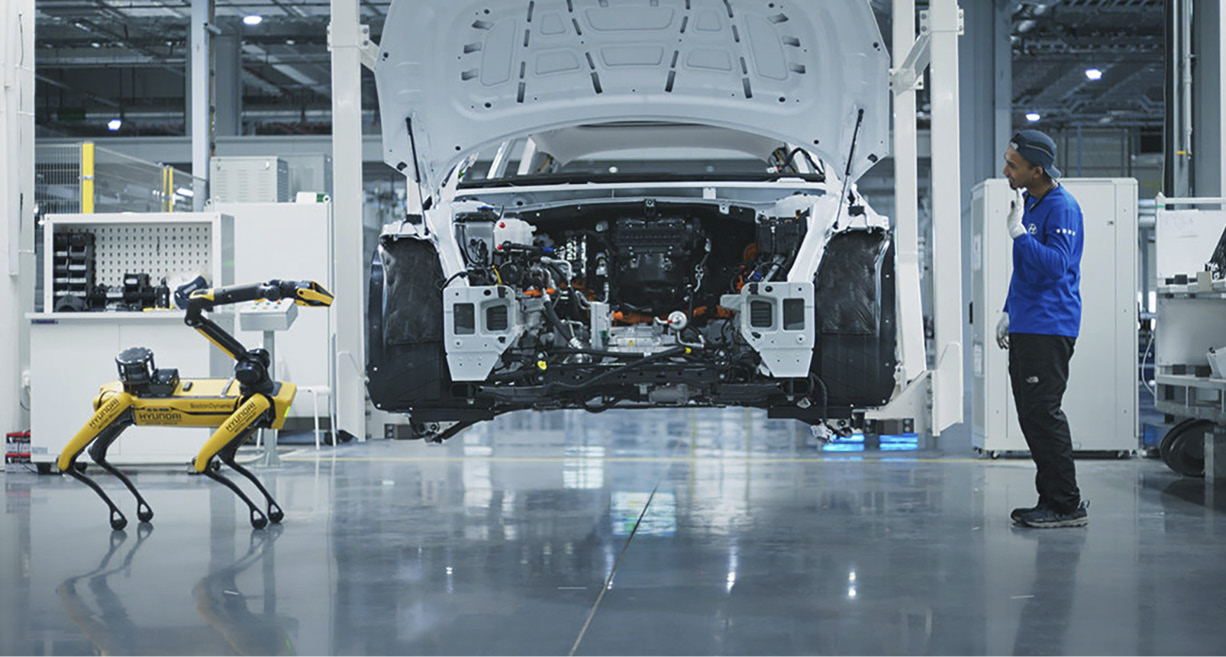 공장에서 작업 중인 로봇, 차량, 사람의 모습