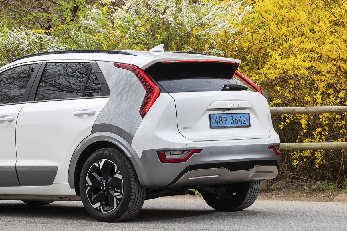 The rear of the Niro EV standing with forsythia in the background