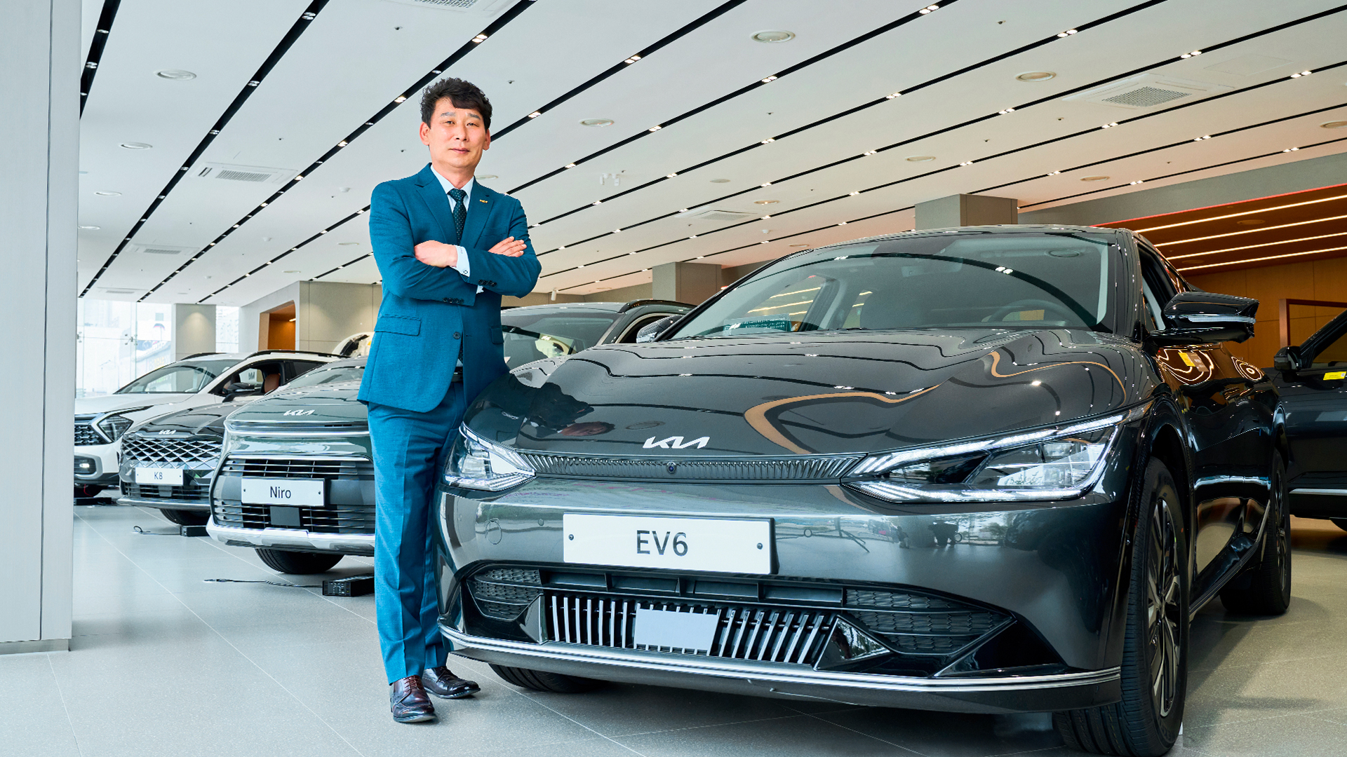 중년 신사가 전기차 옆에서 포즈를 취한 모습