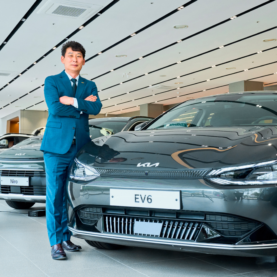 중년 신사가 전기차 옆에서 포즈를 취한 모습