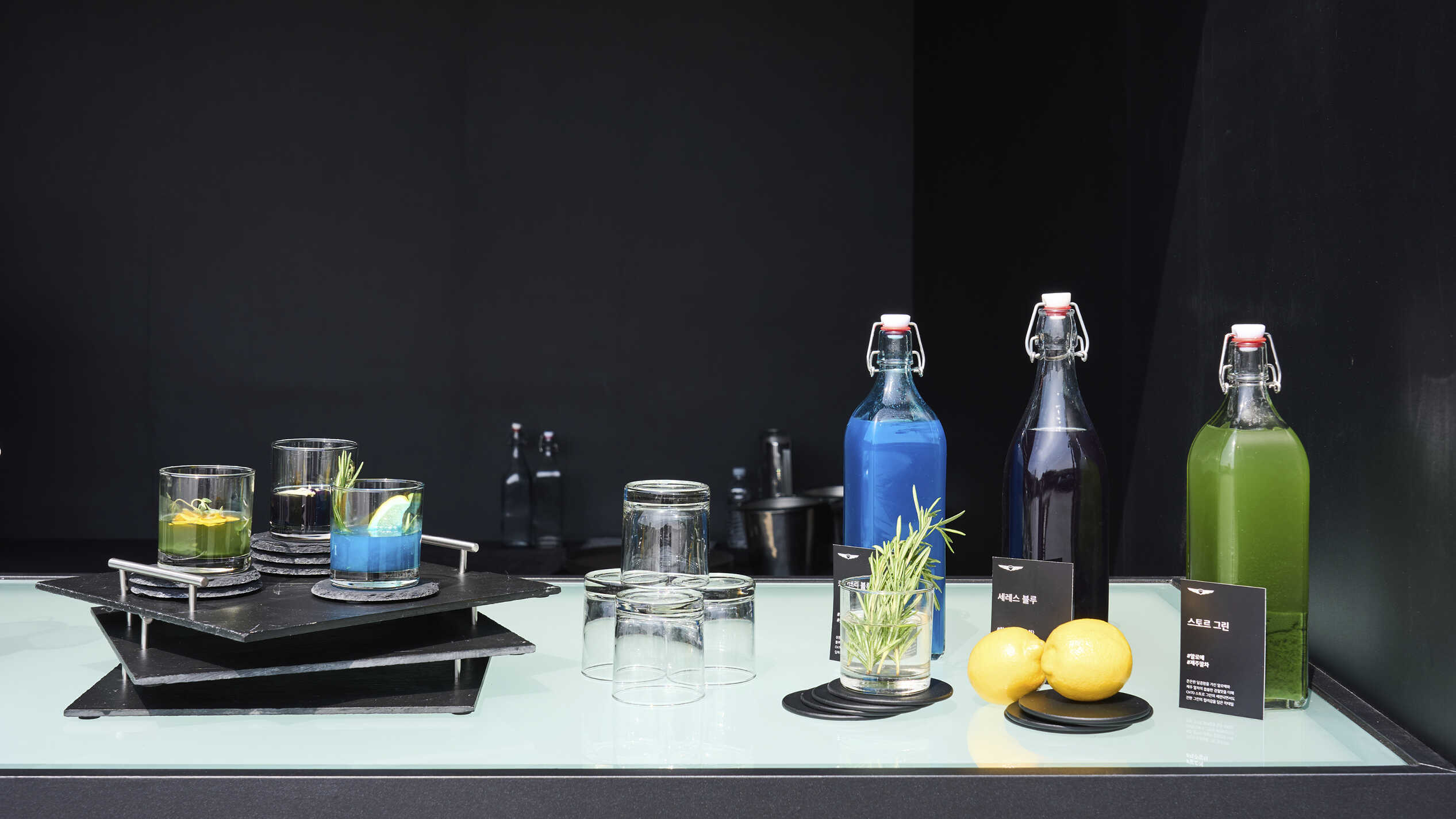 초록색, 파란색, 보라색 음료가 각각 담긴 유리잔과 유리병이 나열된 모습