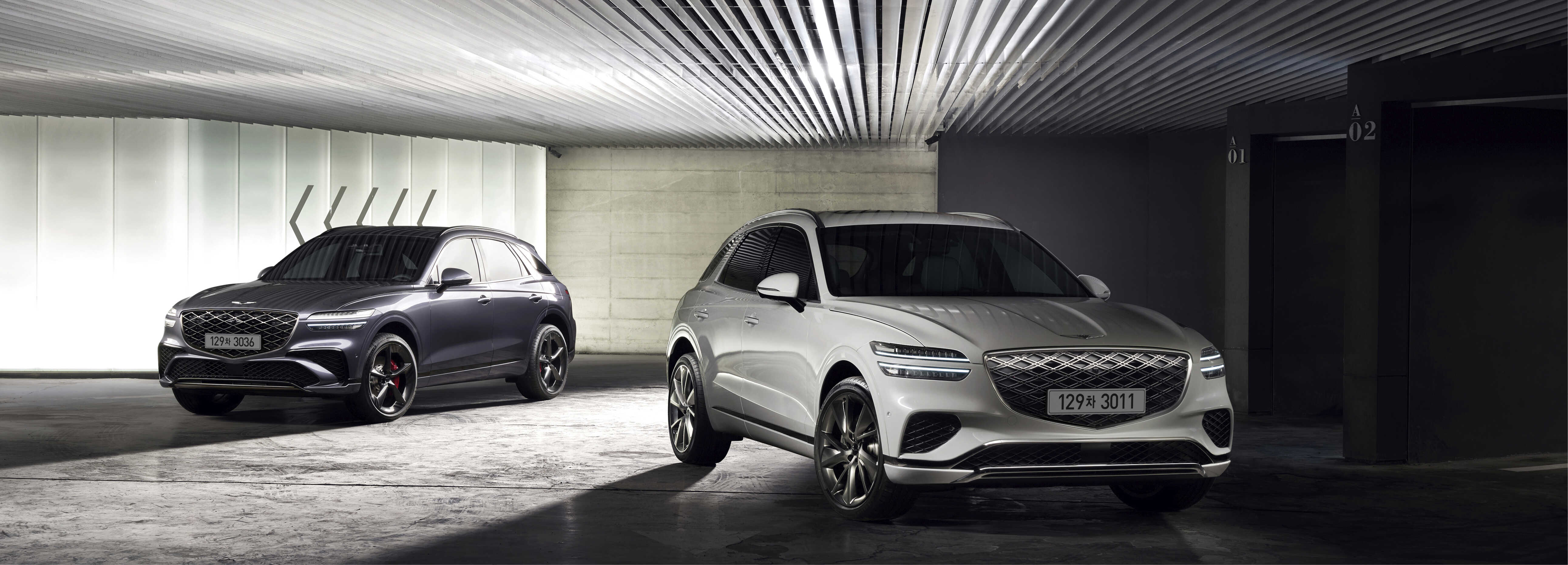 A front view of two medium-sized SUVs, white and gray, placed in a dark interior facing left and right, respectively