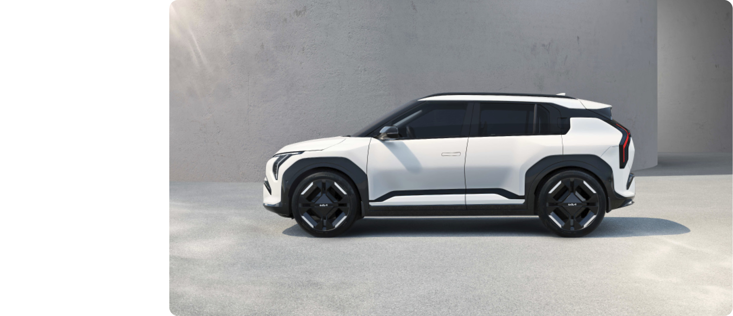 회색 건물과 바닥에 주차된 흰색 소형 SUV 전측면 모습