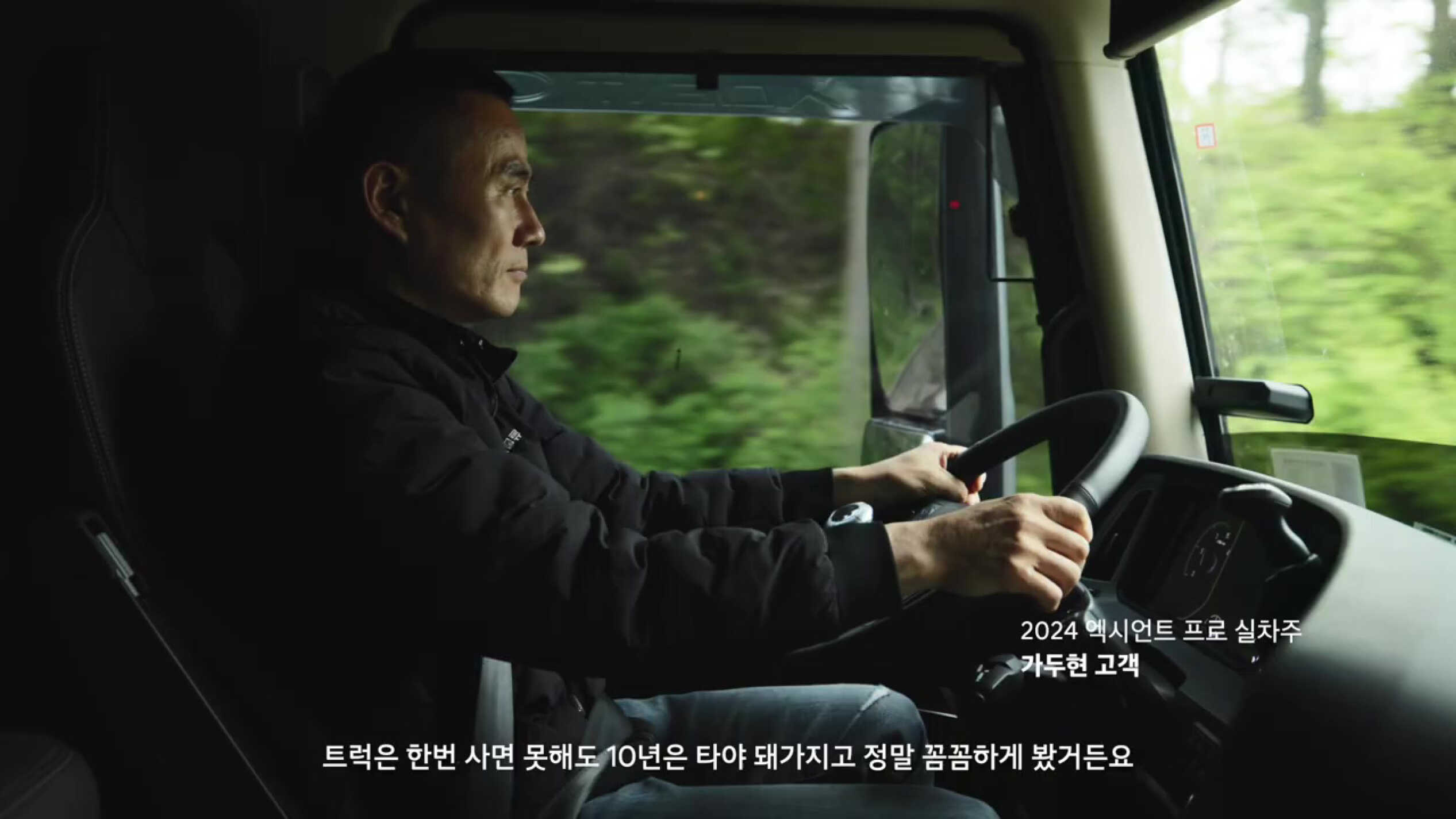 a side view of a male trucker sitting in the driver's seat
