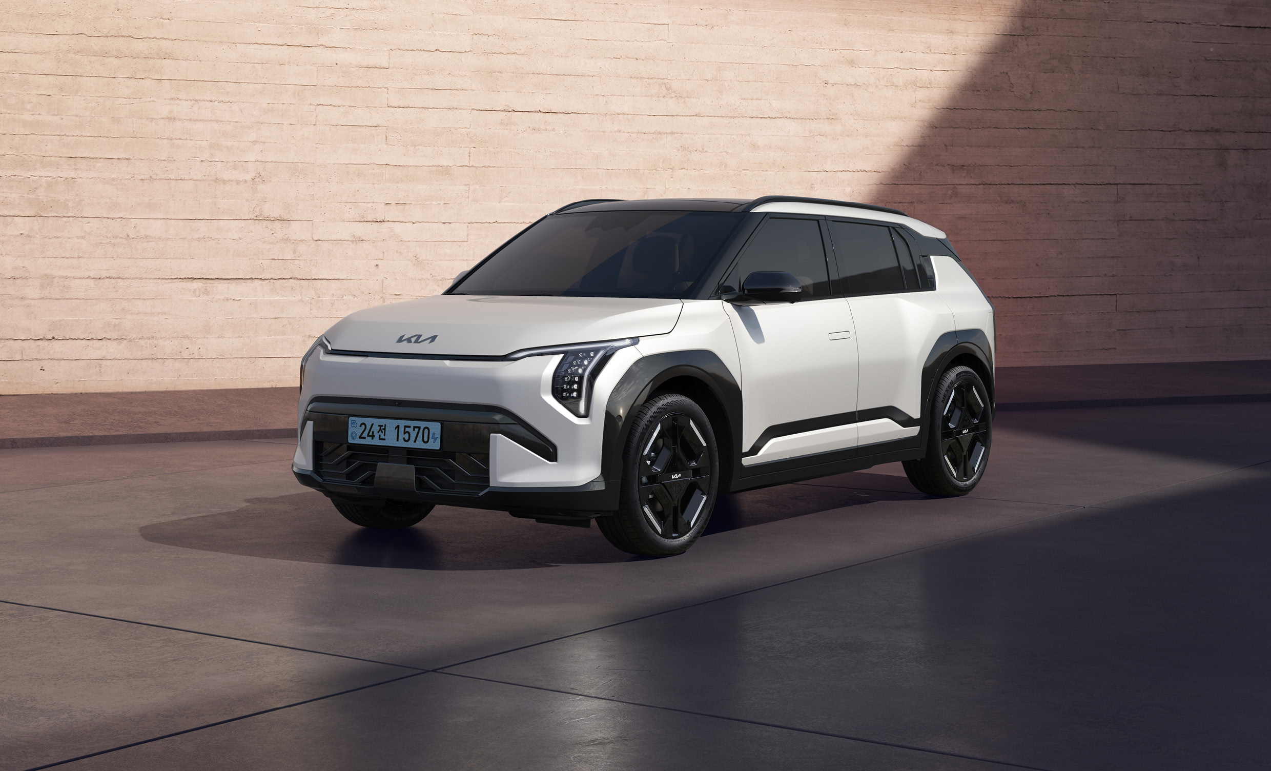 오렌지색 벽을 배경으로 흰색 EV3 정차한 전측면 모습