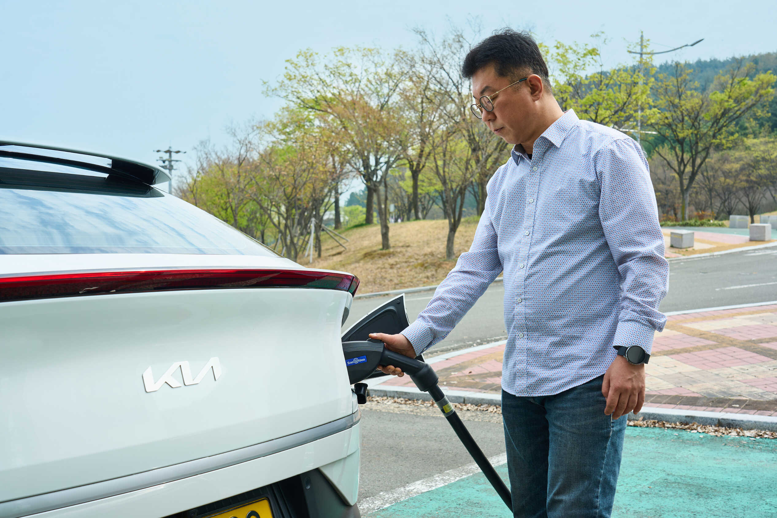 흰색 택시에 충전기를 체결하는 남성의 모습