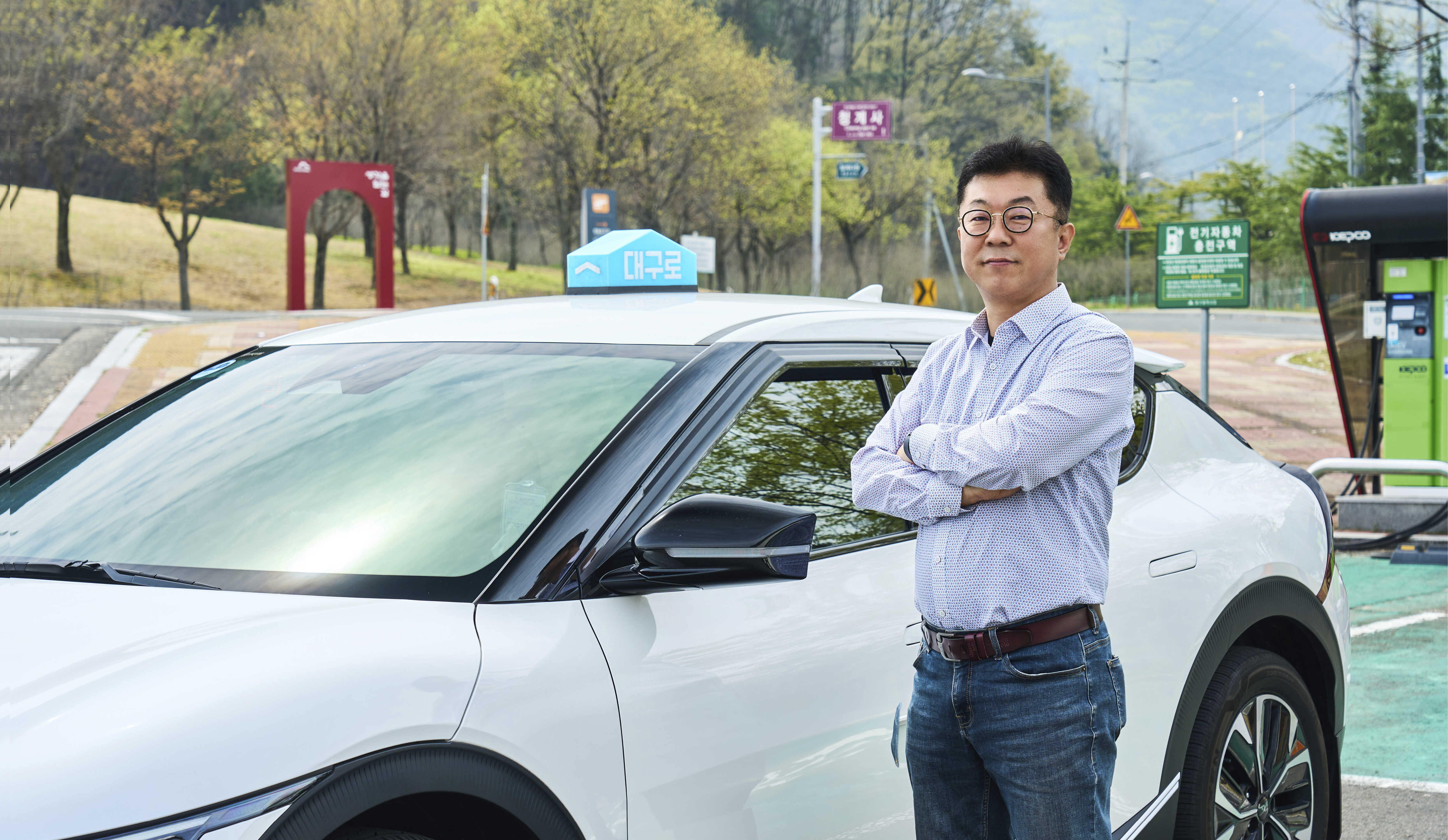 흰색 택시 옆에 선 채 포즈를 취한 남성의 모습