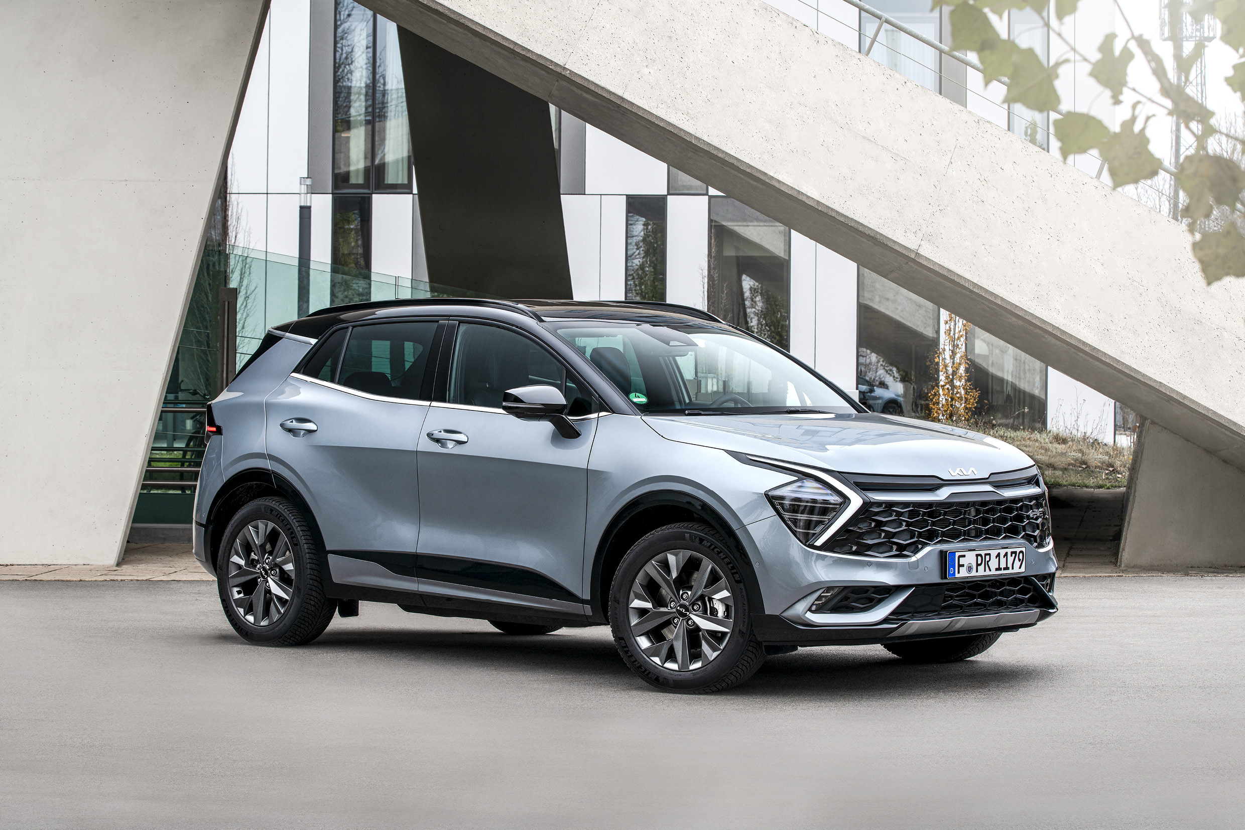 건물 앞에 정차한 은색 스포티지 전측면 모습