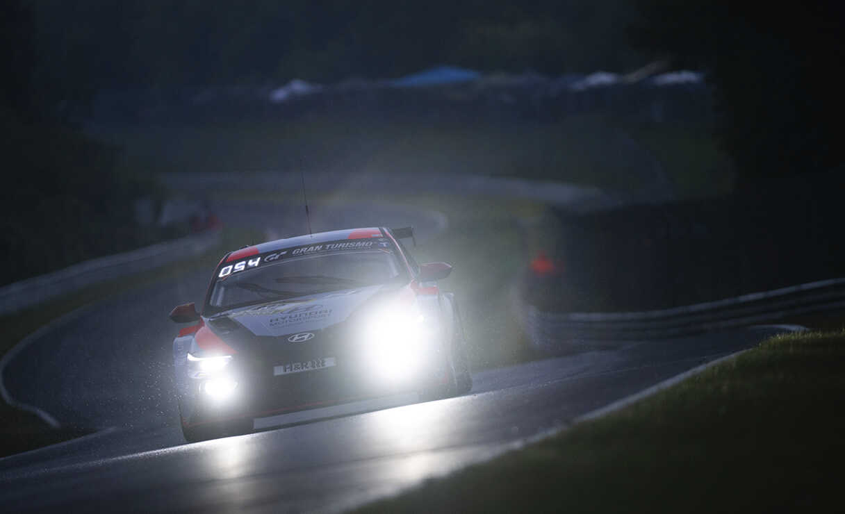 라이트를 켠 아반떼 N TCR이 어두운 서킷을 주행하는 정면 모습