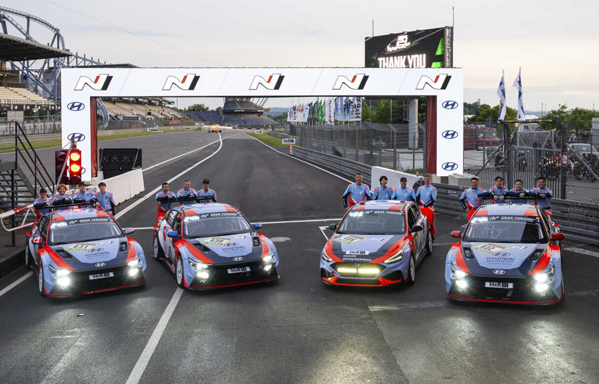 Four Hyundai N TCRs posed with drivers and mechanics after stopping in the middle of the circuit course