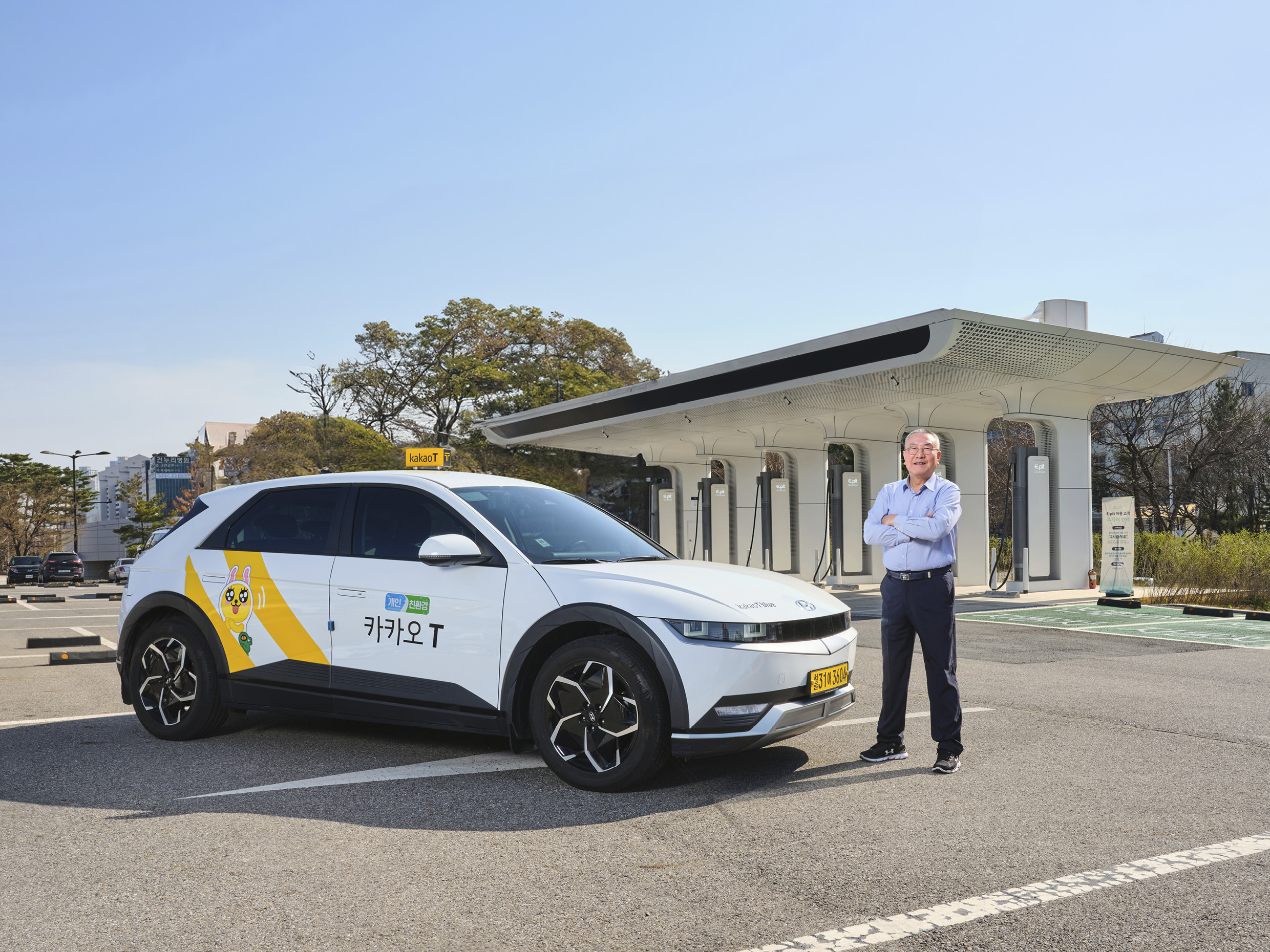 전기차 충전소에 아이오닉 5 택시와 택시기사가 포즈를 취한 채 서 있는 모습