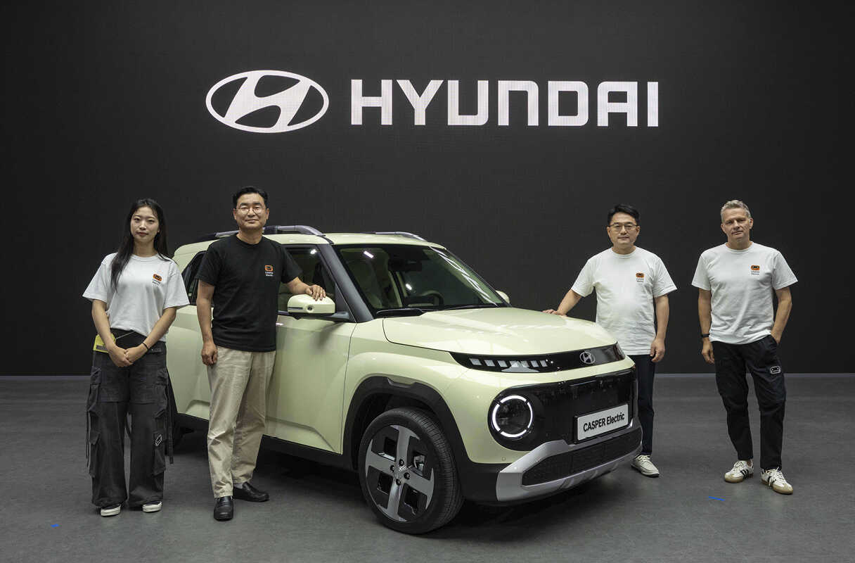 라임색 캐스퍼 일렉트릭 주변으로 네 명의 성인이 포즈를 취한 모습