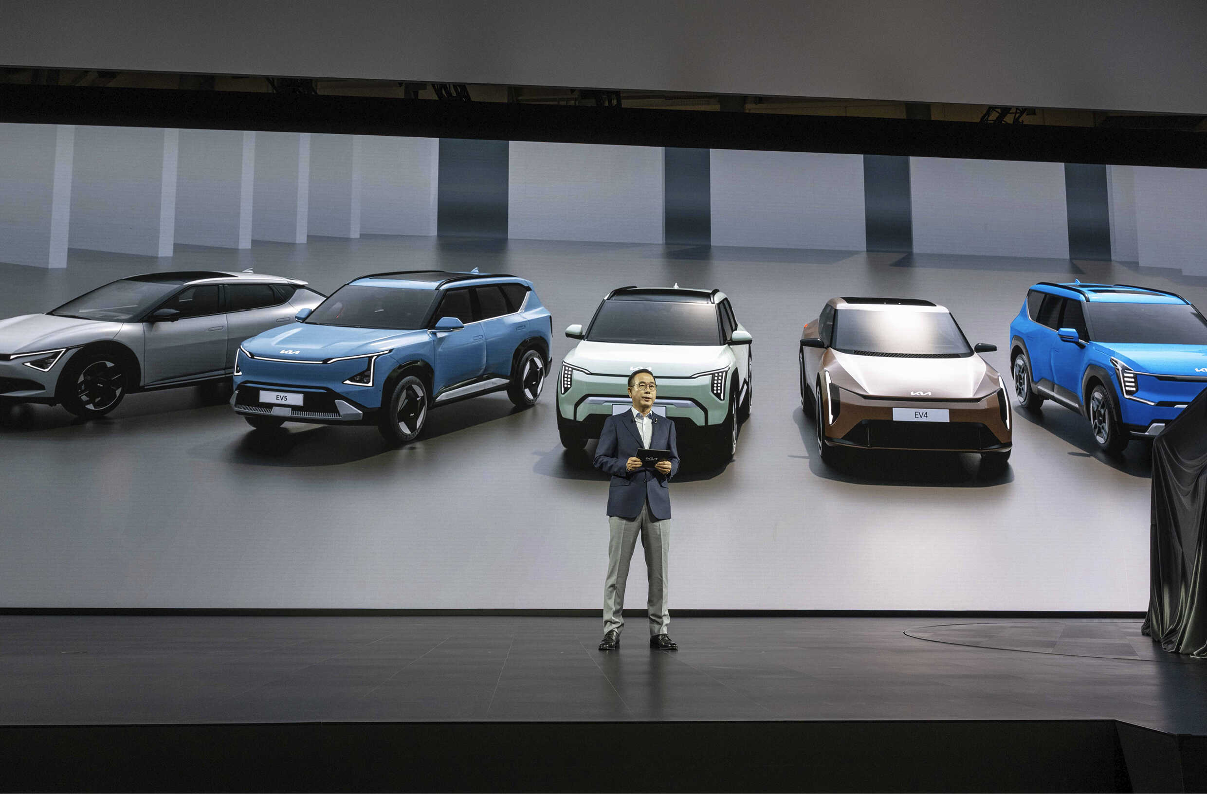 무대 위 화면에 자동차 사진을 띄운 앞에 남성이 서 있는 모습