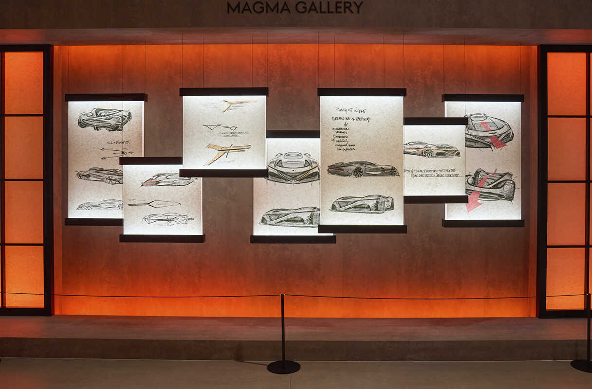 오렌지색 벽면에 콘셉트카 스케치가 전시된 모습