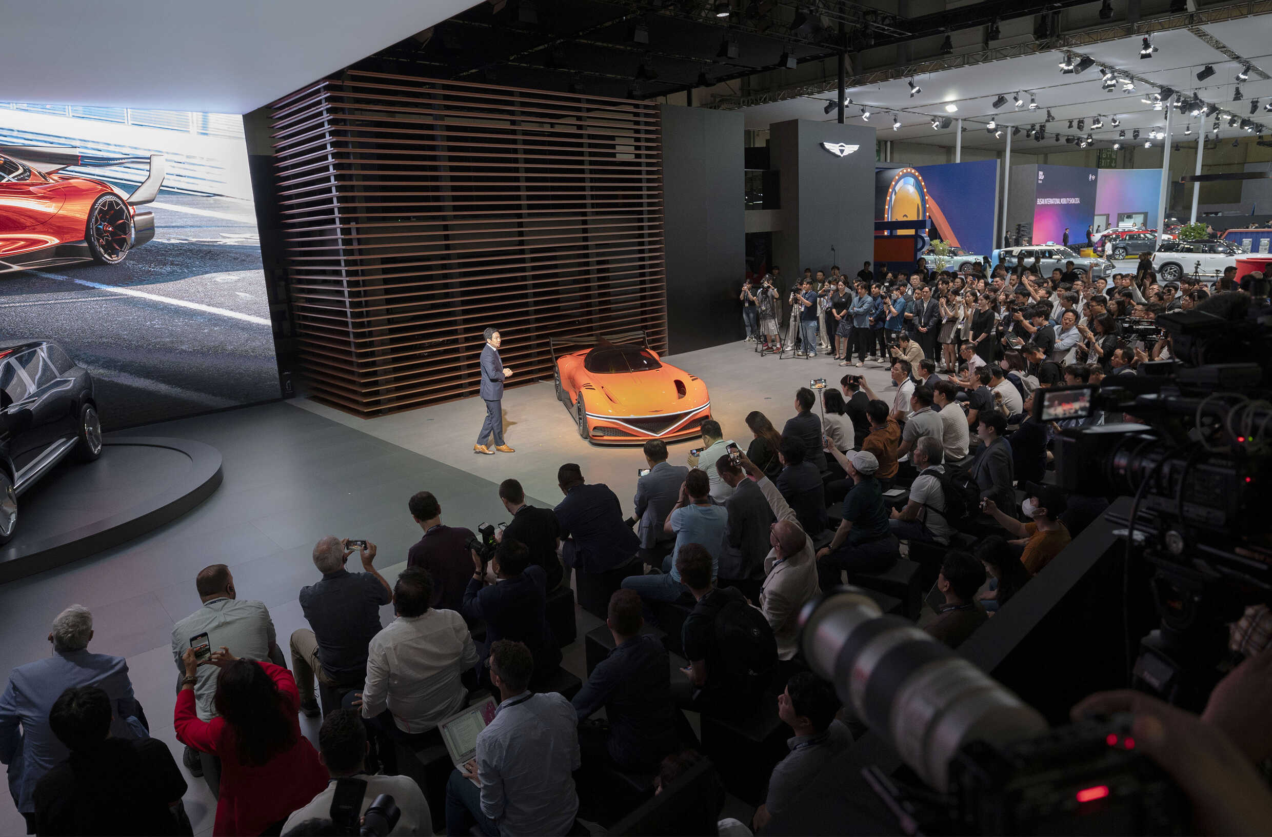 오렌지색 콘셉트카를 전시한 무대에 남성이 설명하는 모습