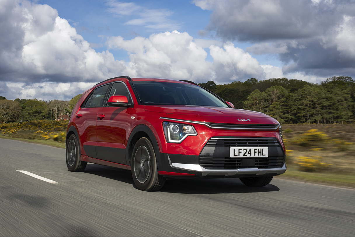 숲길을 주행하는 빨간색 해치백 전측면 모습