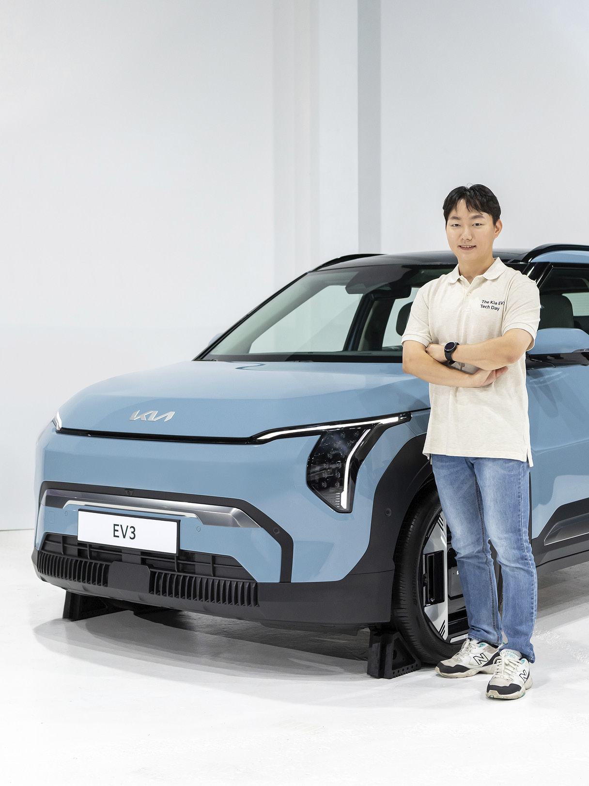 하늘색 자동차 옆에 성인 남성이 팔짱을 낀 채 선 모습