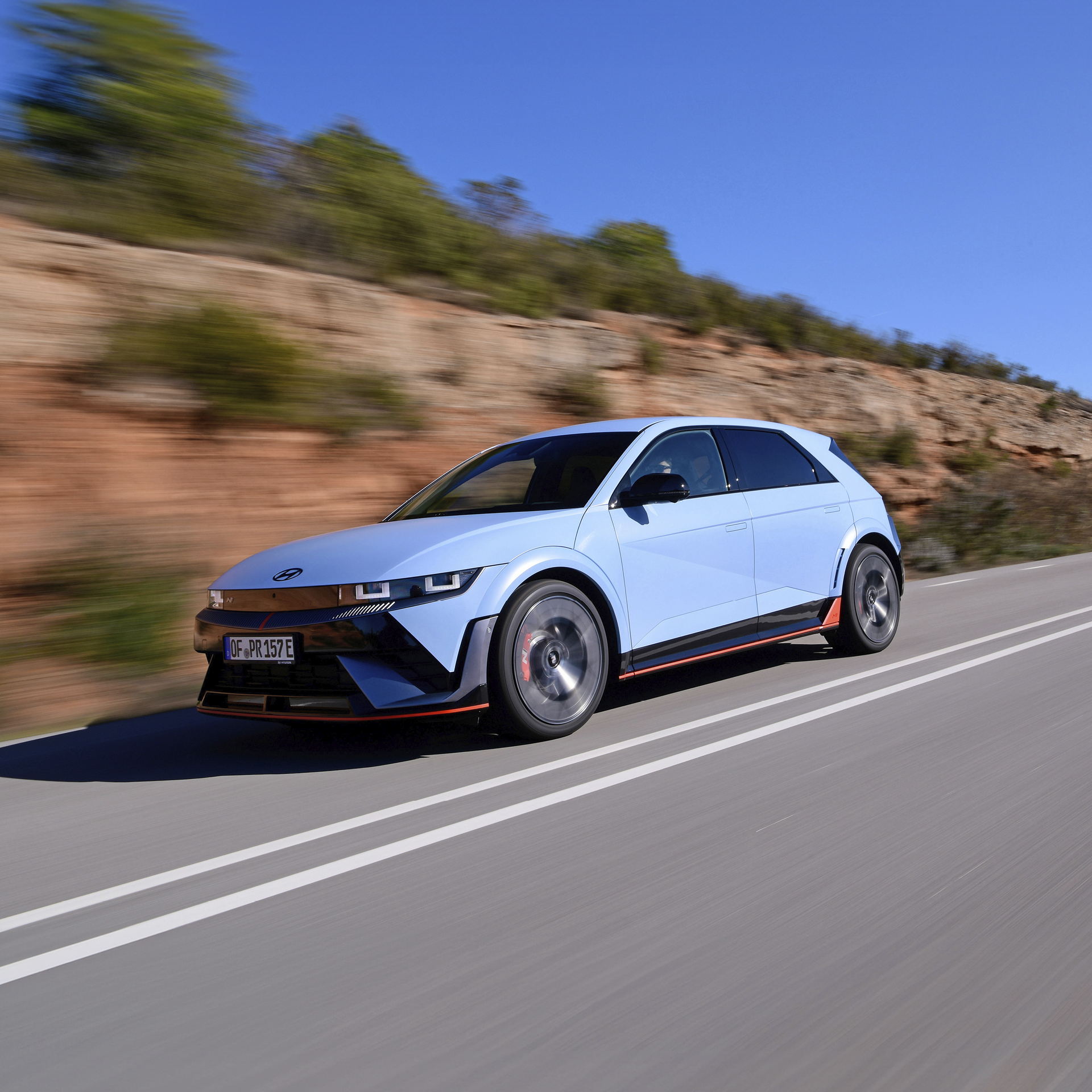 교외 도로를 주행하는 하늘색 해치백 전측면 모습