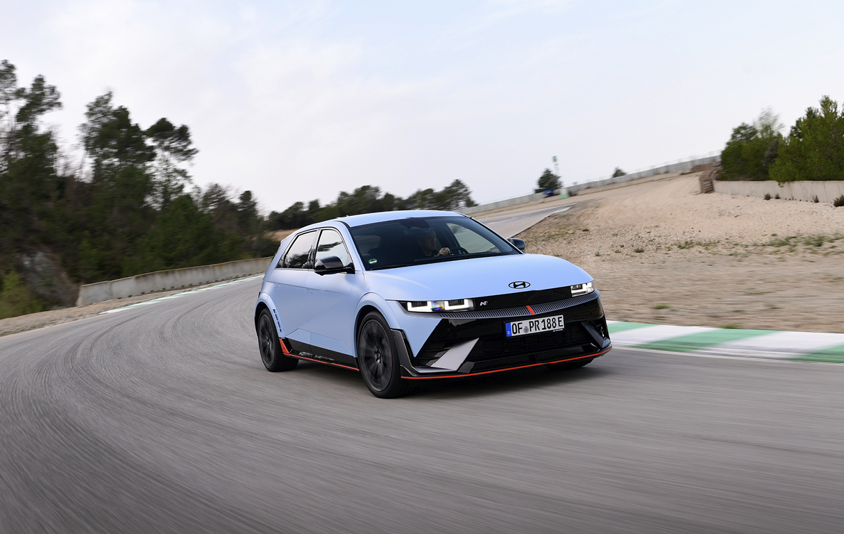 하늘색 해치백이 서킷 코너를 주행하는 전측면 모습