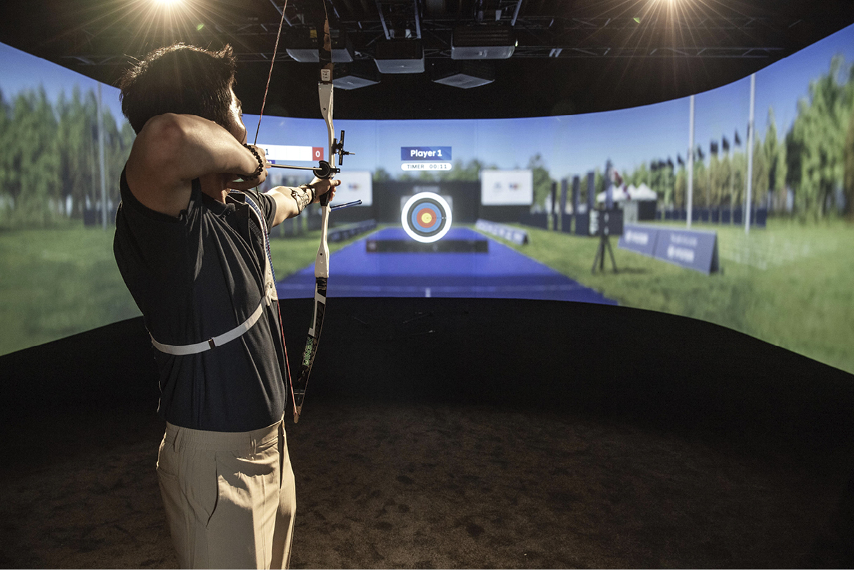 A male athlete pulling a bow demonstration from a virtual archery experience equipment