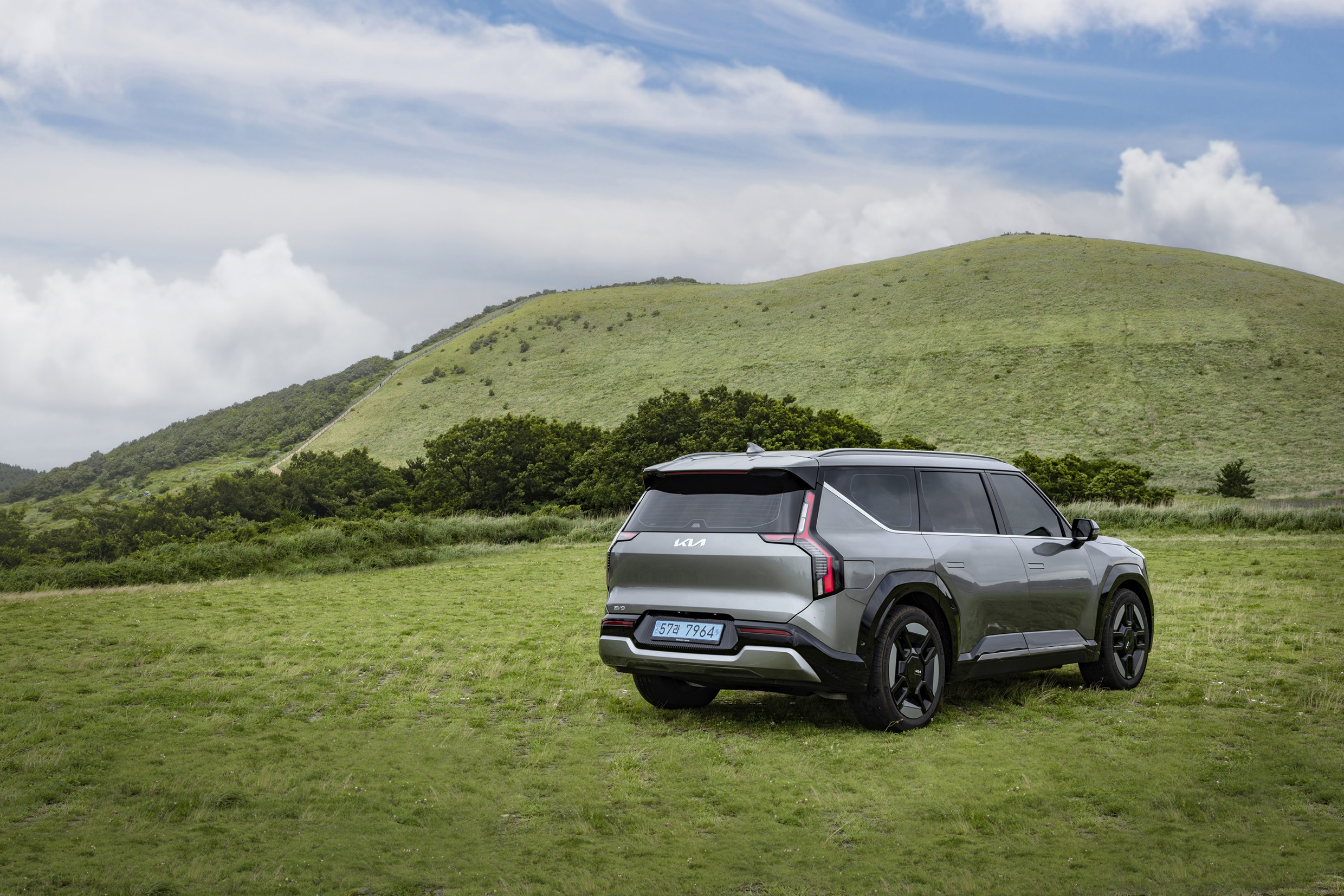 회색 SUV가 오름을 배경으로 정차한 후측면 모습