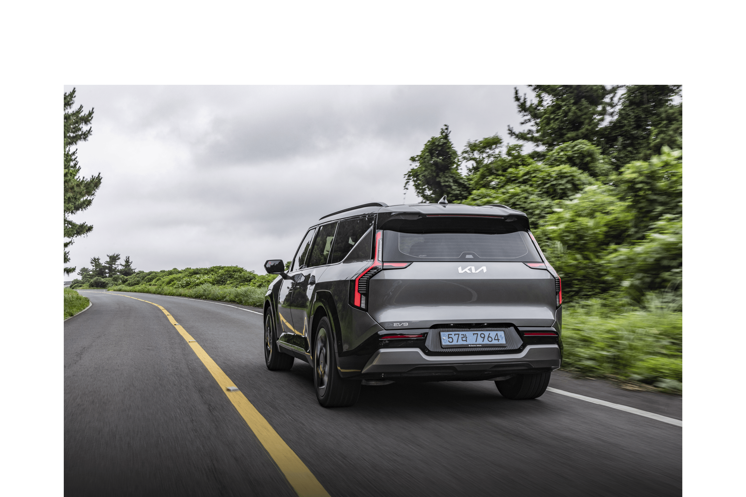 A rear view of a gray SUV driving down a mountain path