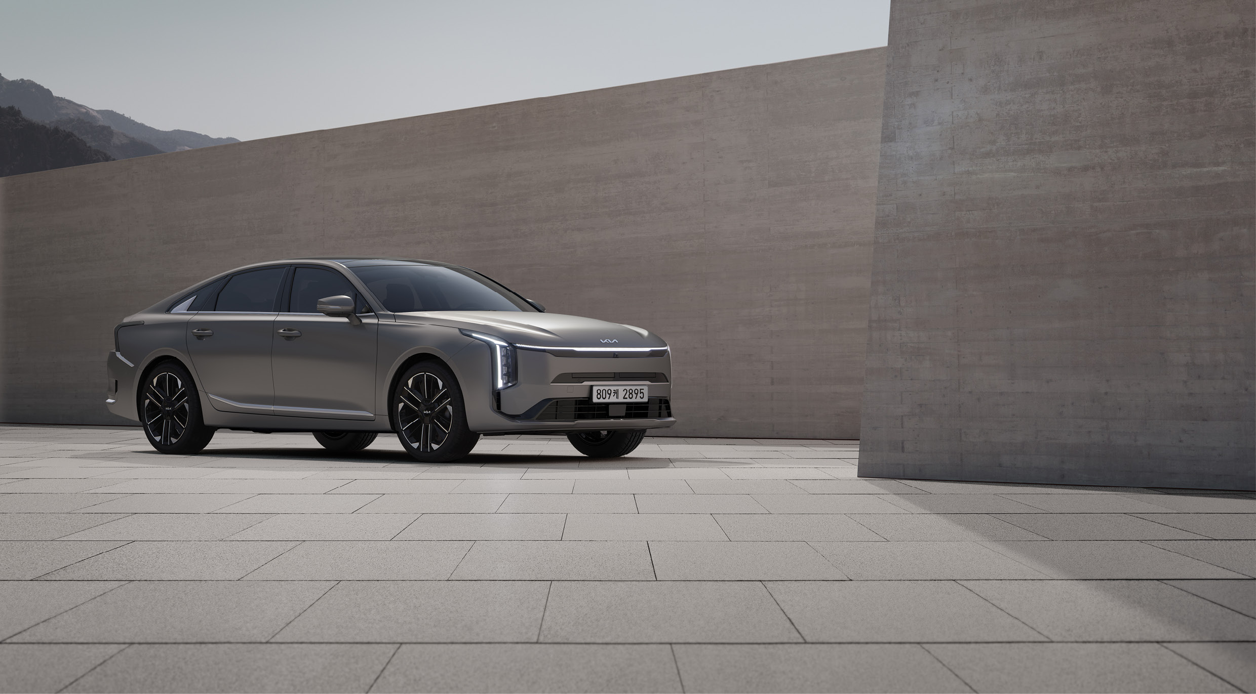 베이지 색 타일과 타일 벽 옆에 자동차가 정차한 전측면 모습