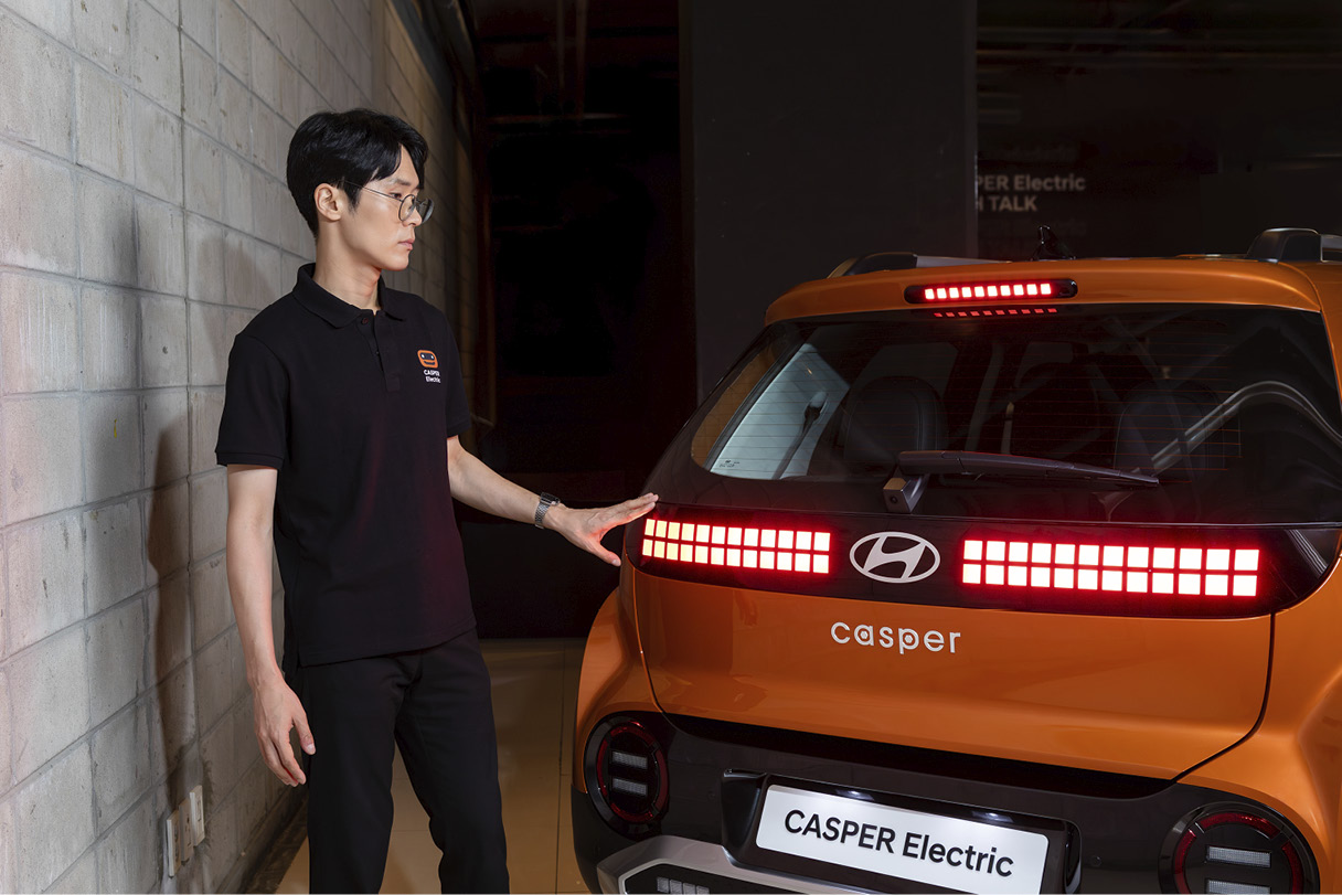 후면 램프의 옆에서 차량을 바라보는 남자 연구원의 모습