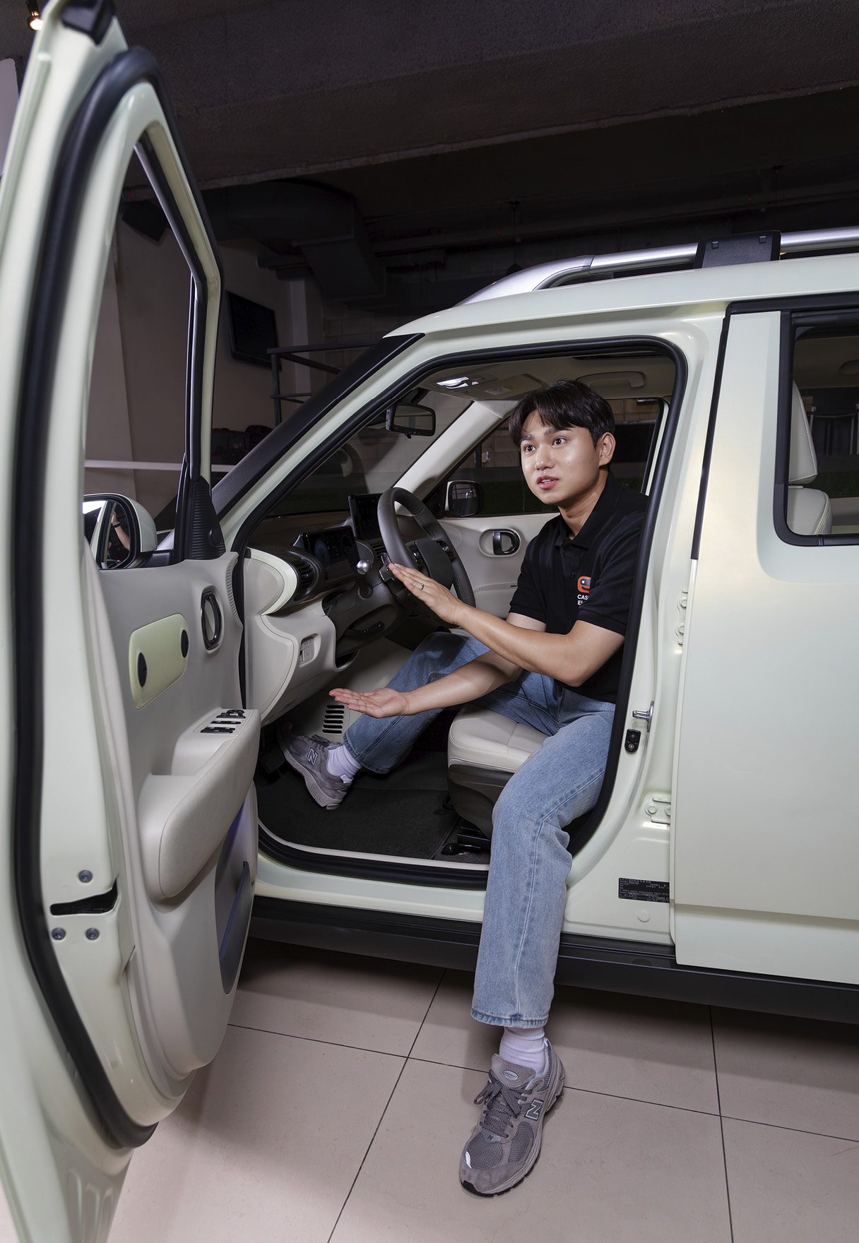 운전석에 살짝 걸터앉아 차량의 기능에 대해 설명하는 남자 연구원의 모습