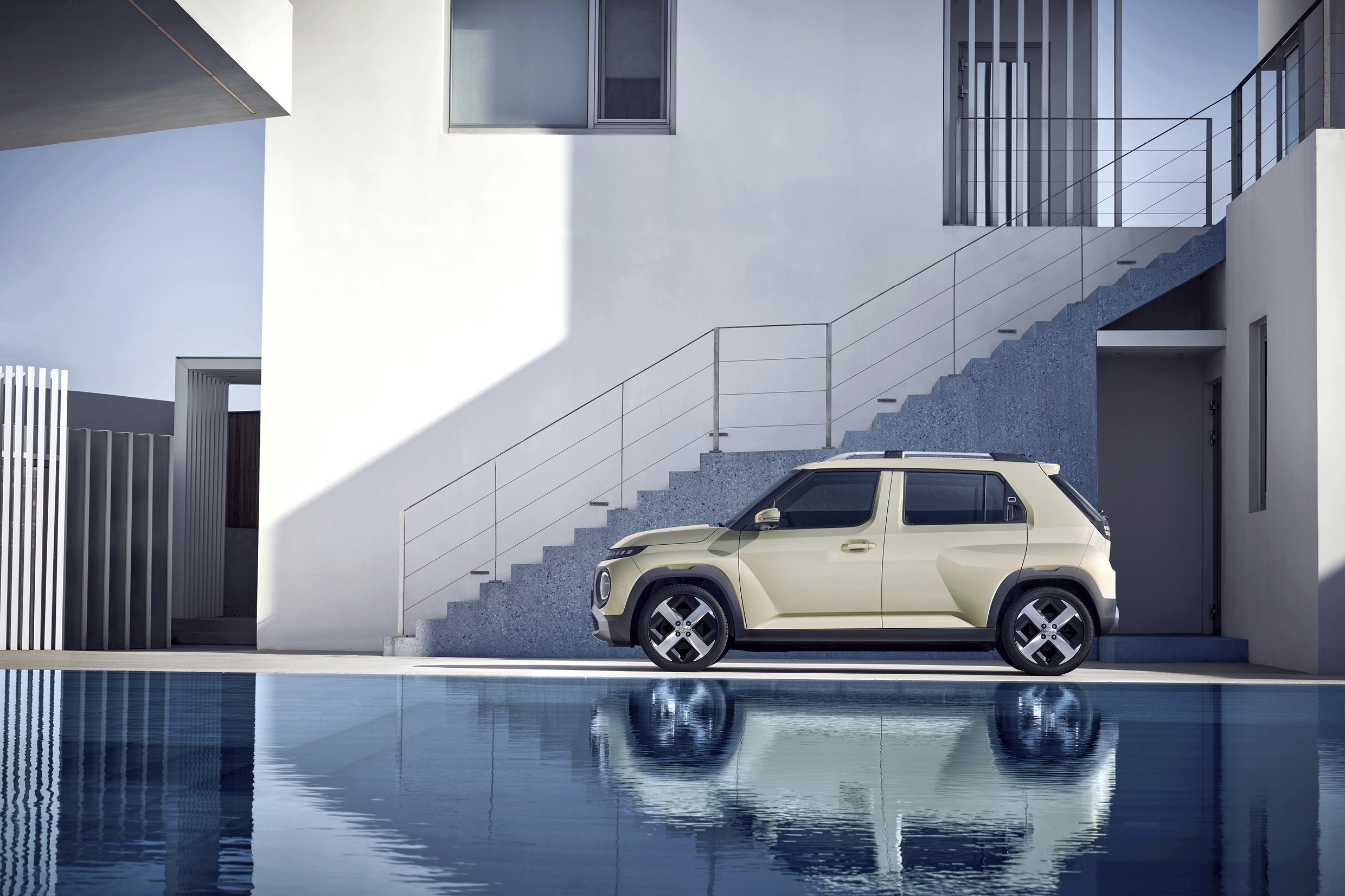 하얀색 건물과 투명의 물이 가득한 수영장 사이에 서있는 차량의 측면