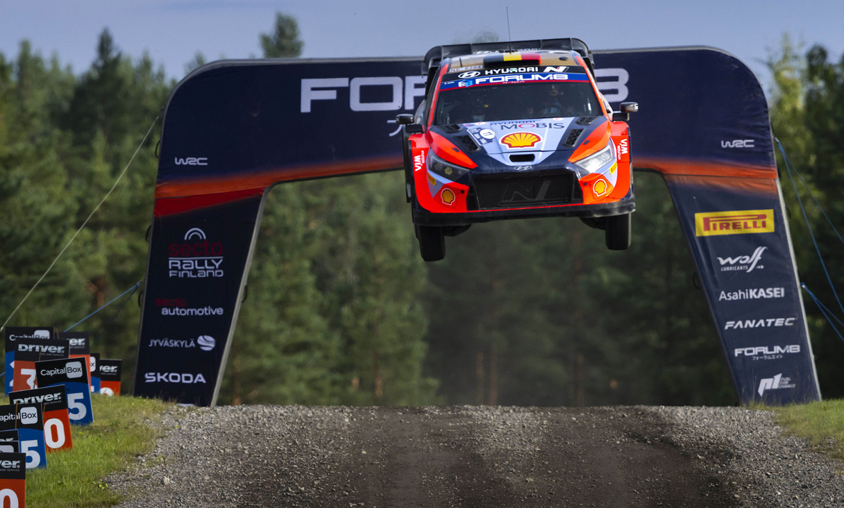 A rally car jumping high and coming down the hill