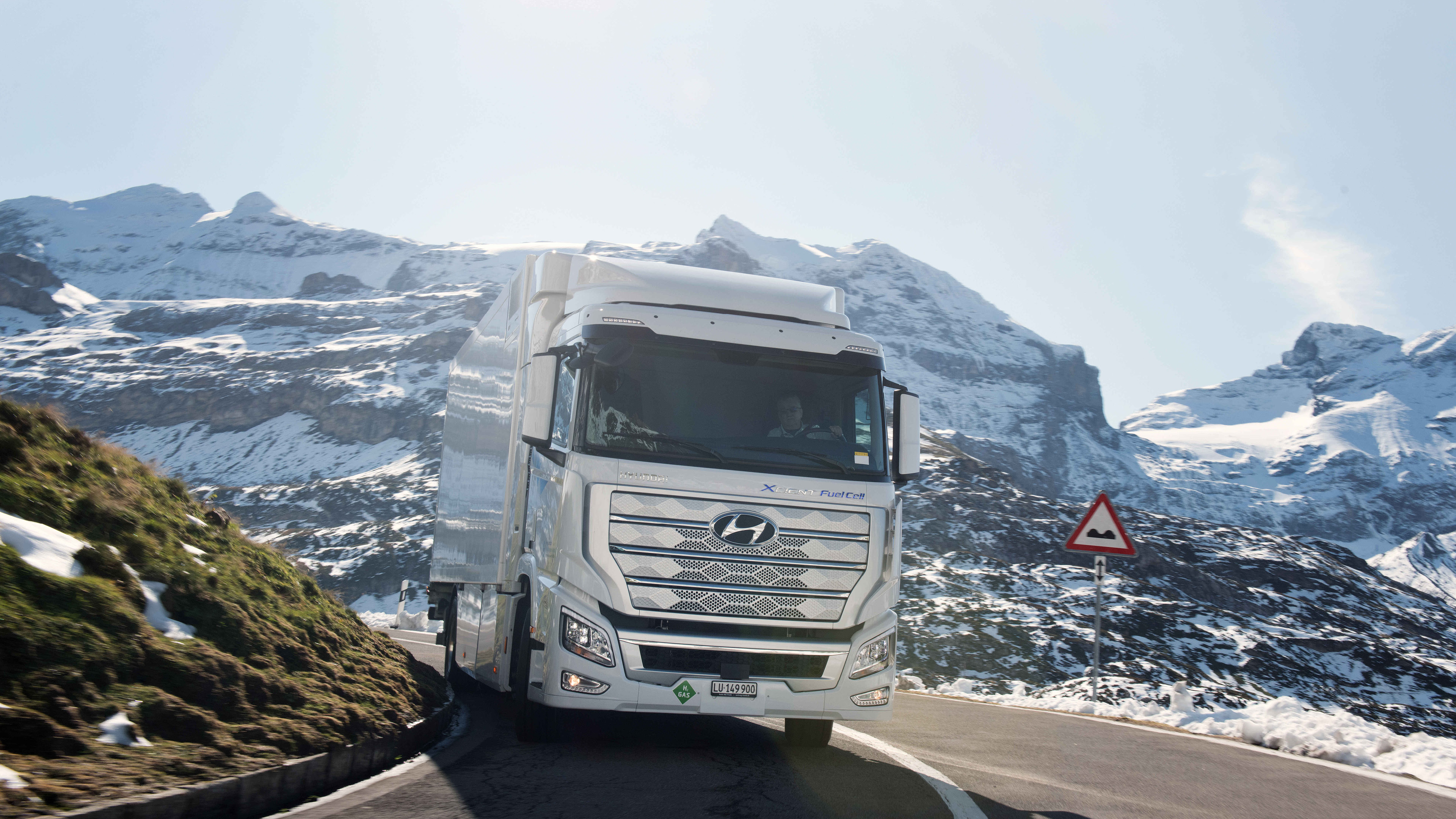 A large white truck driving down a mountain path