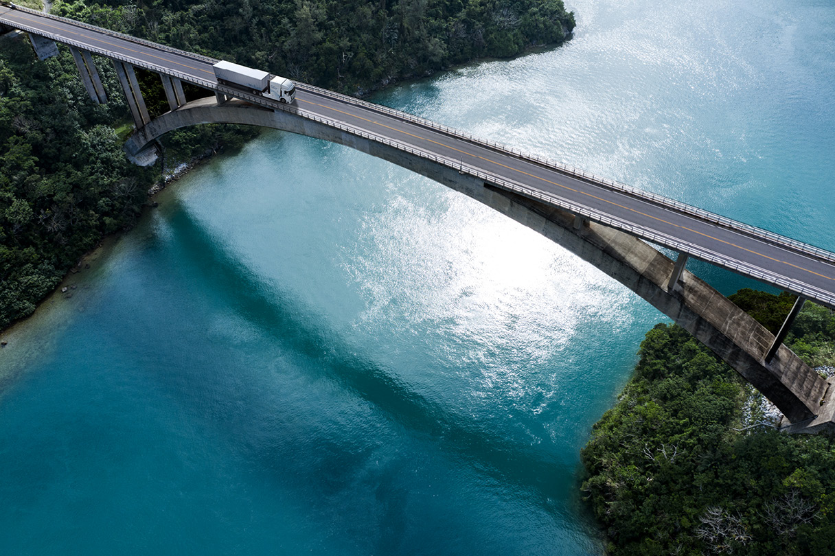 Aerial footage of a white large truck driving on a bridge over the river