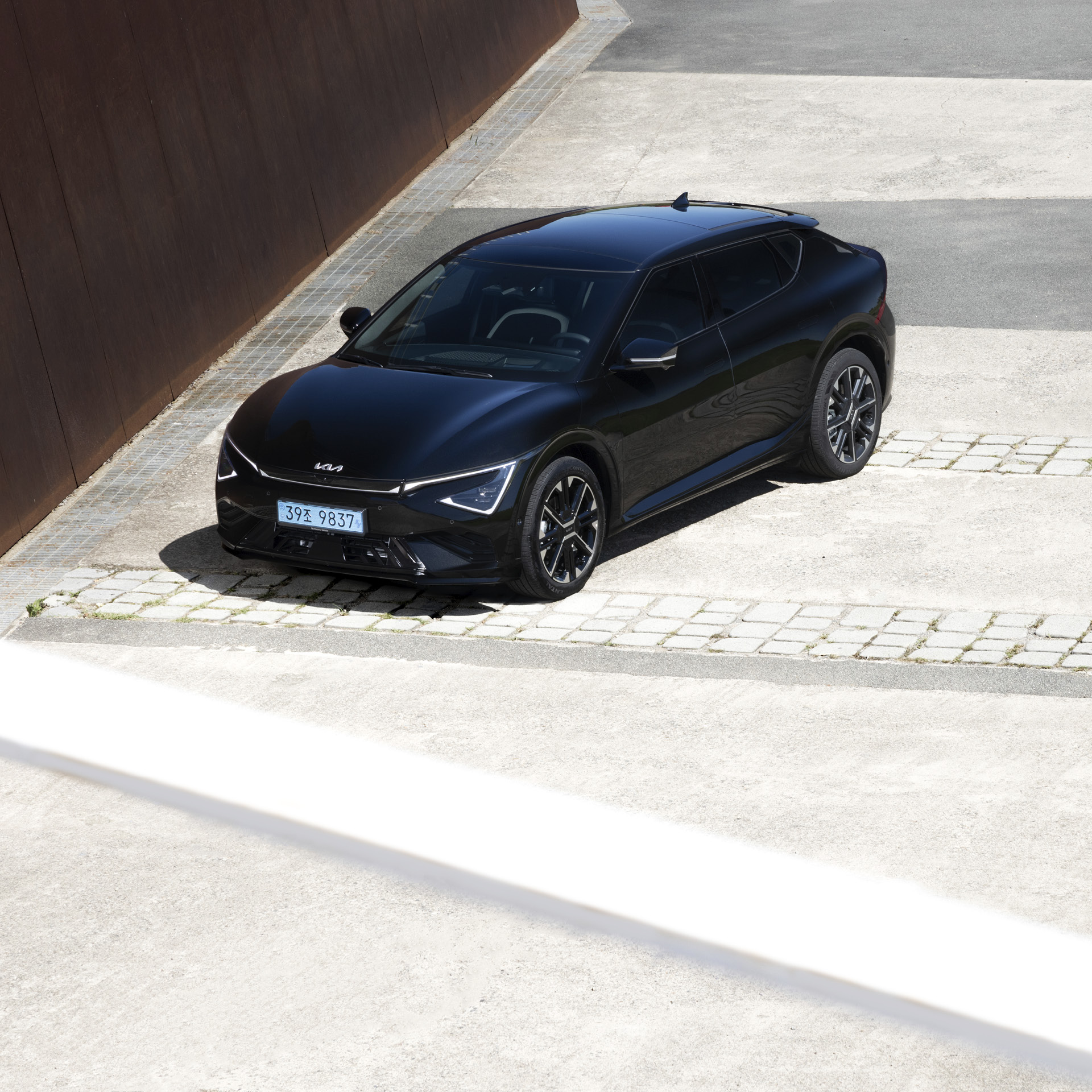 검은색 전기차가 하얀색 대지 위에 정차한 전측면 모습