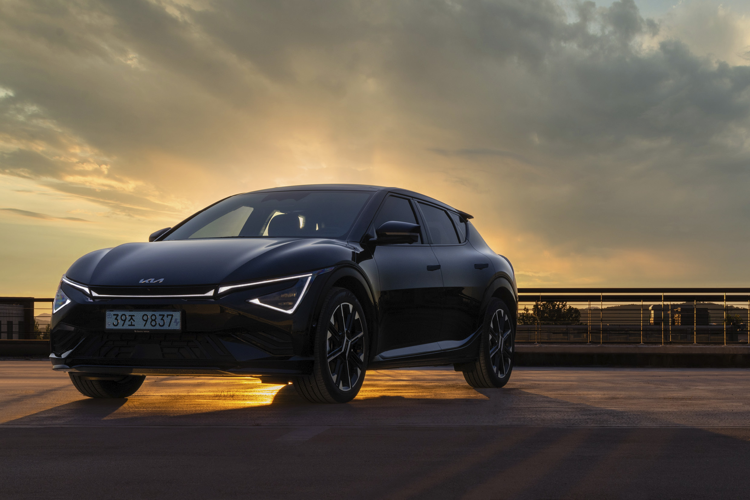 검은색 전기차가 석양을 등지고 정차한 전측면 모습