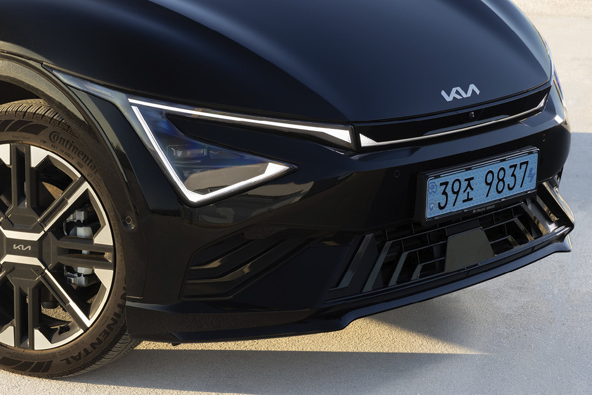 A front view of a black electric car driving on a suburban road