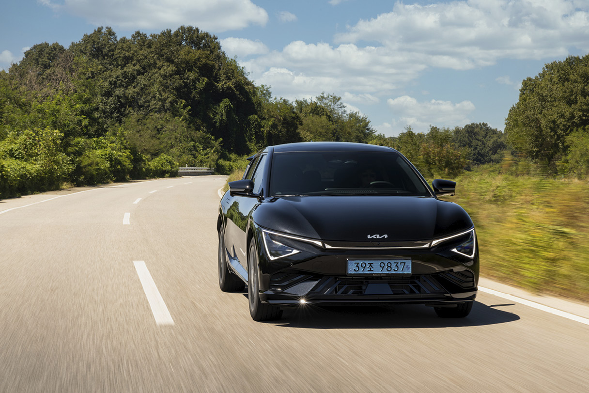 A front view of a black electric car driving on a suburban road