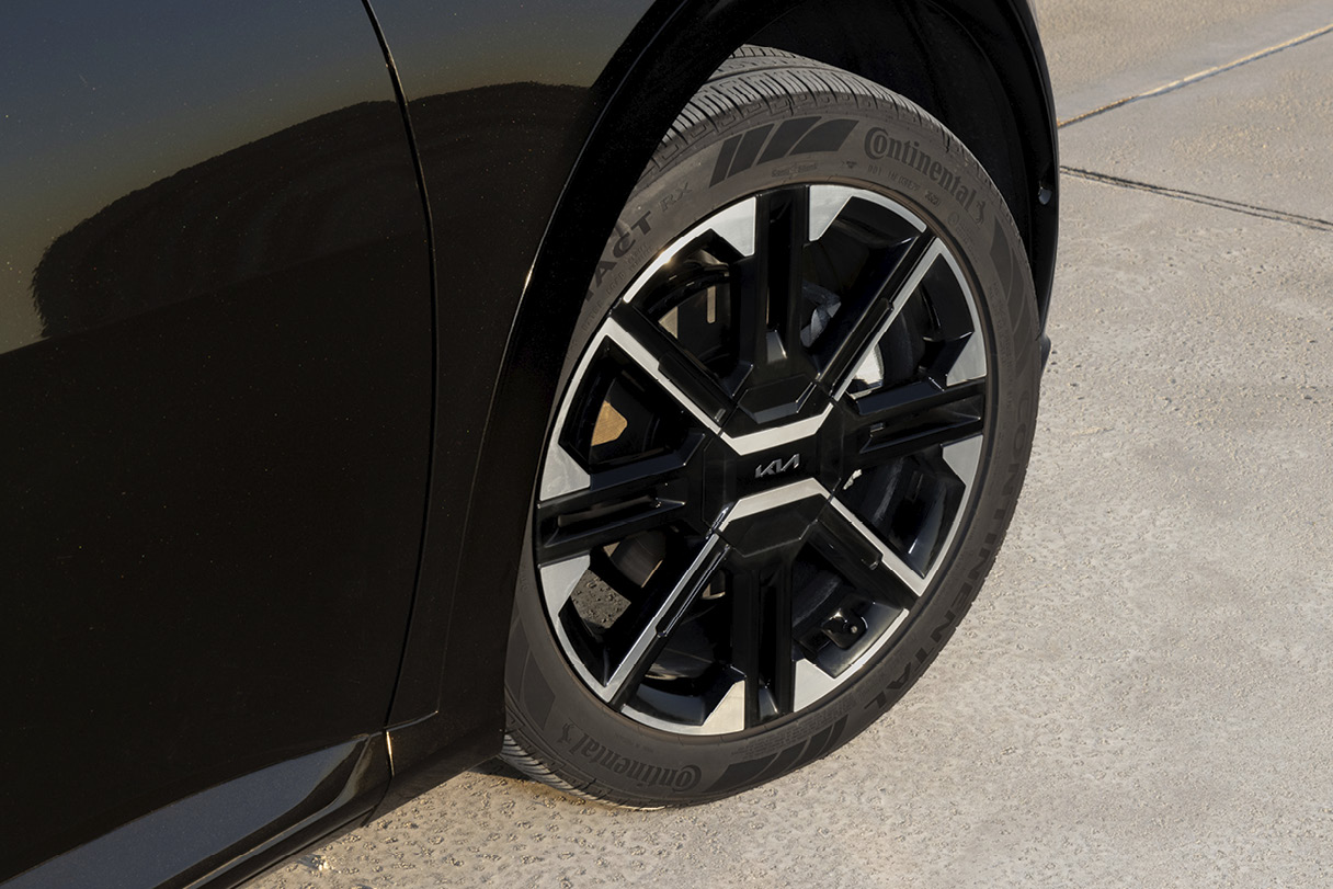 The front wheels of a black electric car illuminated closely