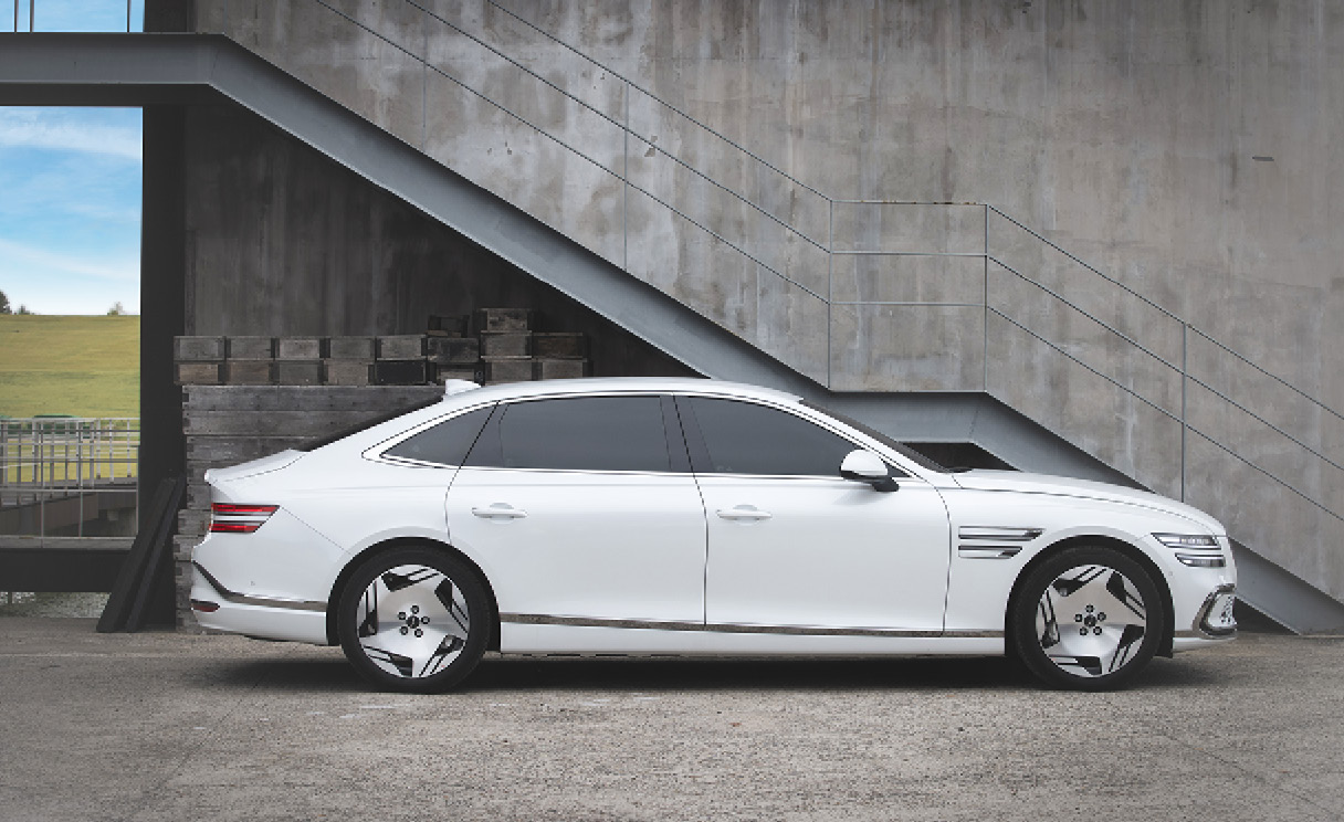 G80 전동화 모델이 구조물 앞에 서 있는 정측면 모습